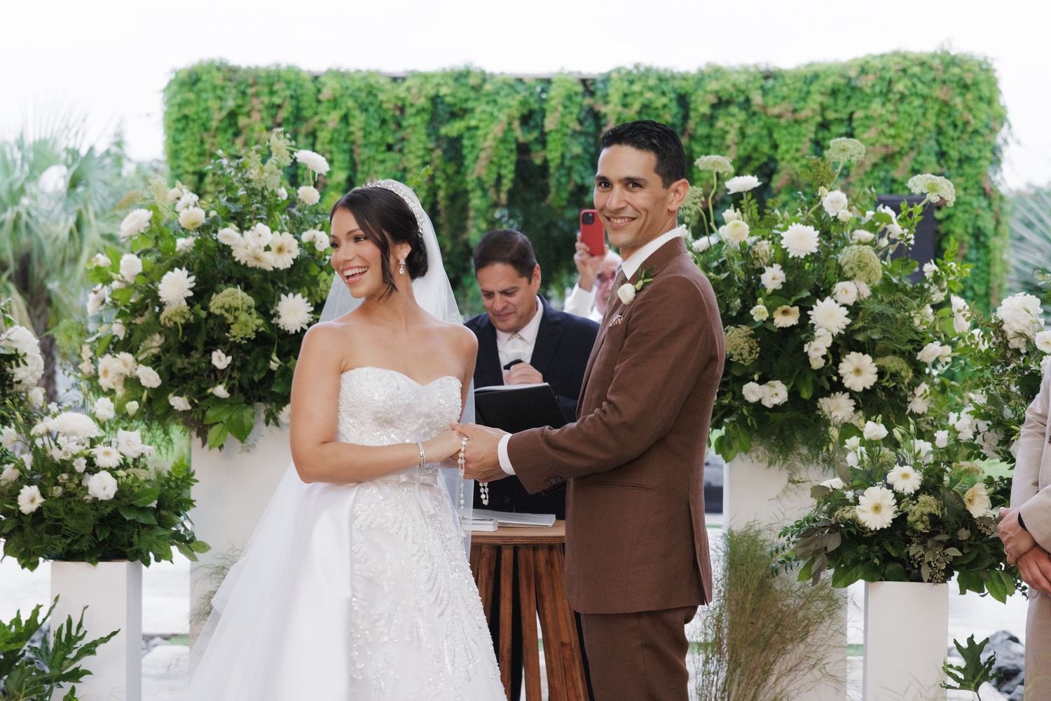 Outdoor wedding ceremony setup with white floral arrangements and natural greenery decorations.