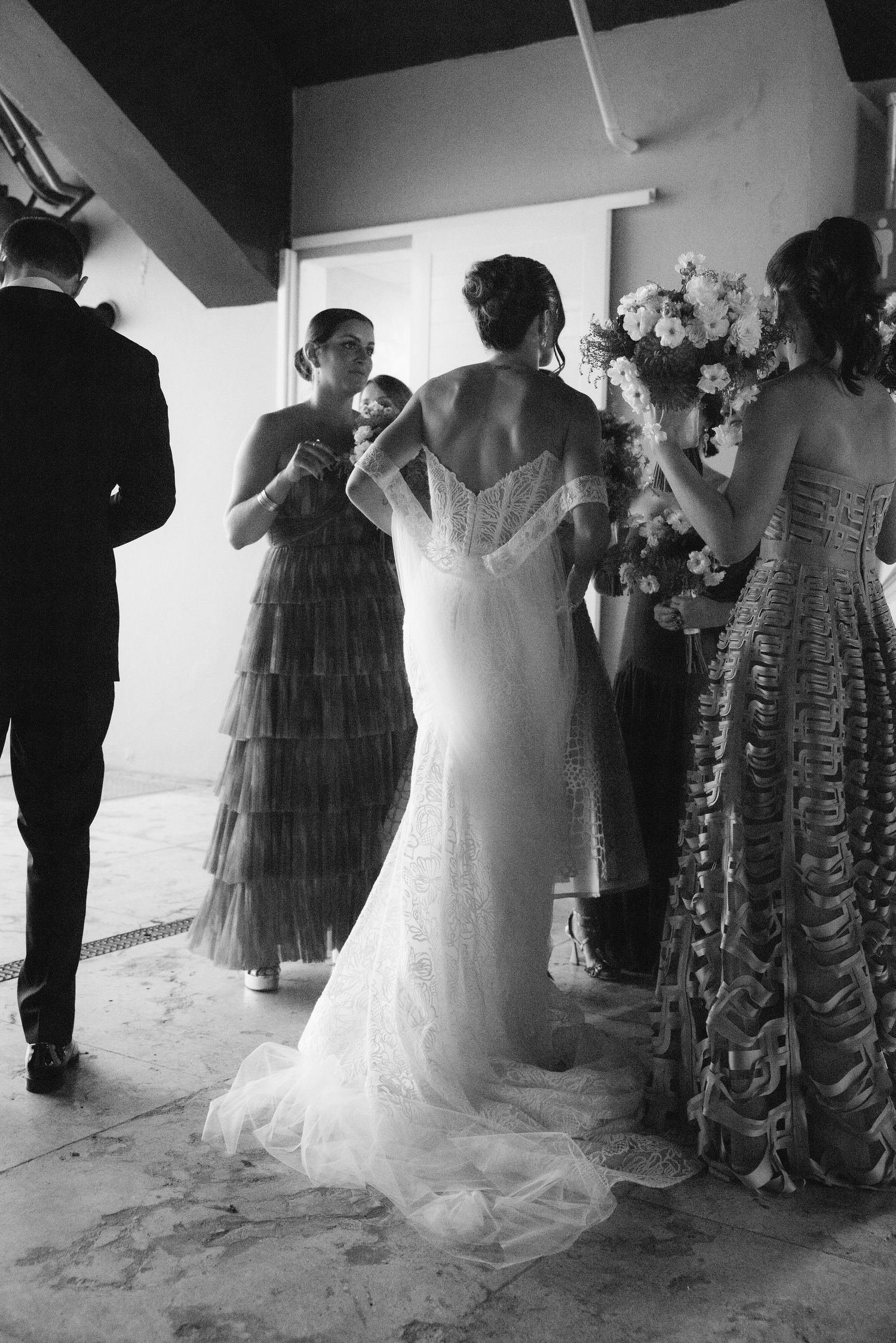 Black and white photo of wedding preparations with elegant dresses and floral arrangements.