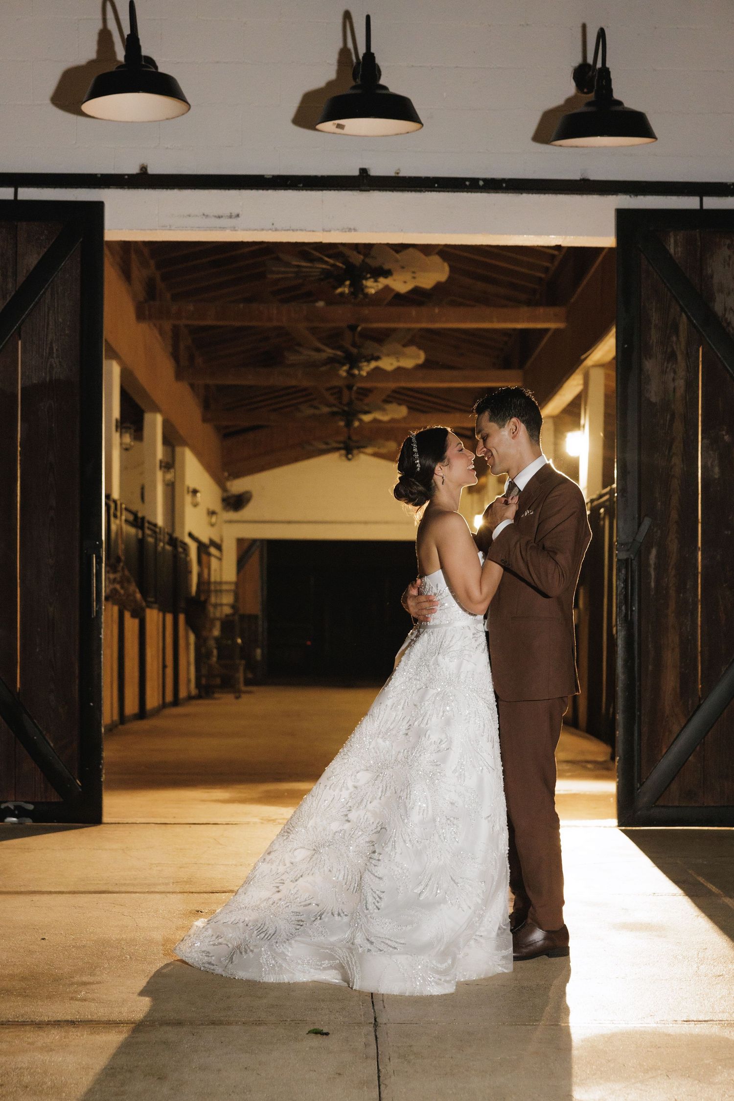 Romantic indoor wedding photography session in a rustic barn venue with dramatic lighting and wooden beams.