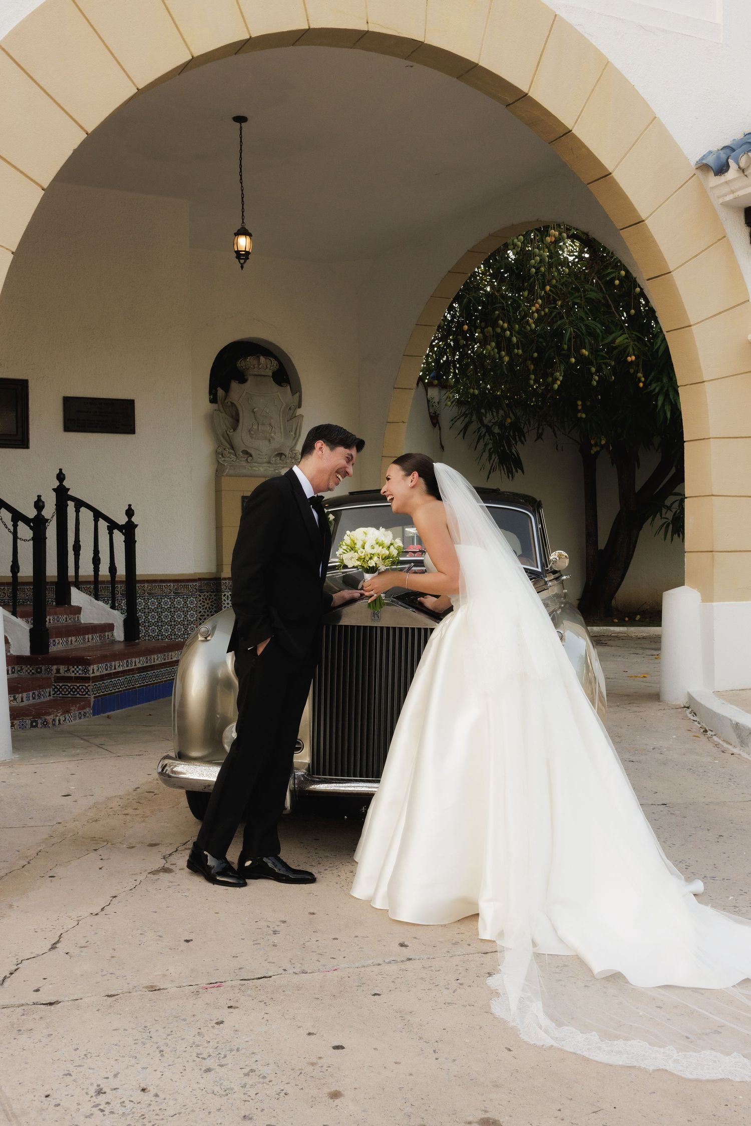A wedding couple shares a romantic moment under a stone archway during their first look photo session.
