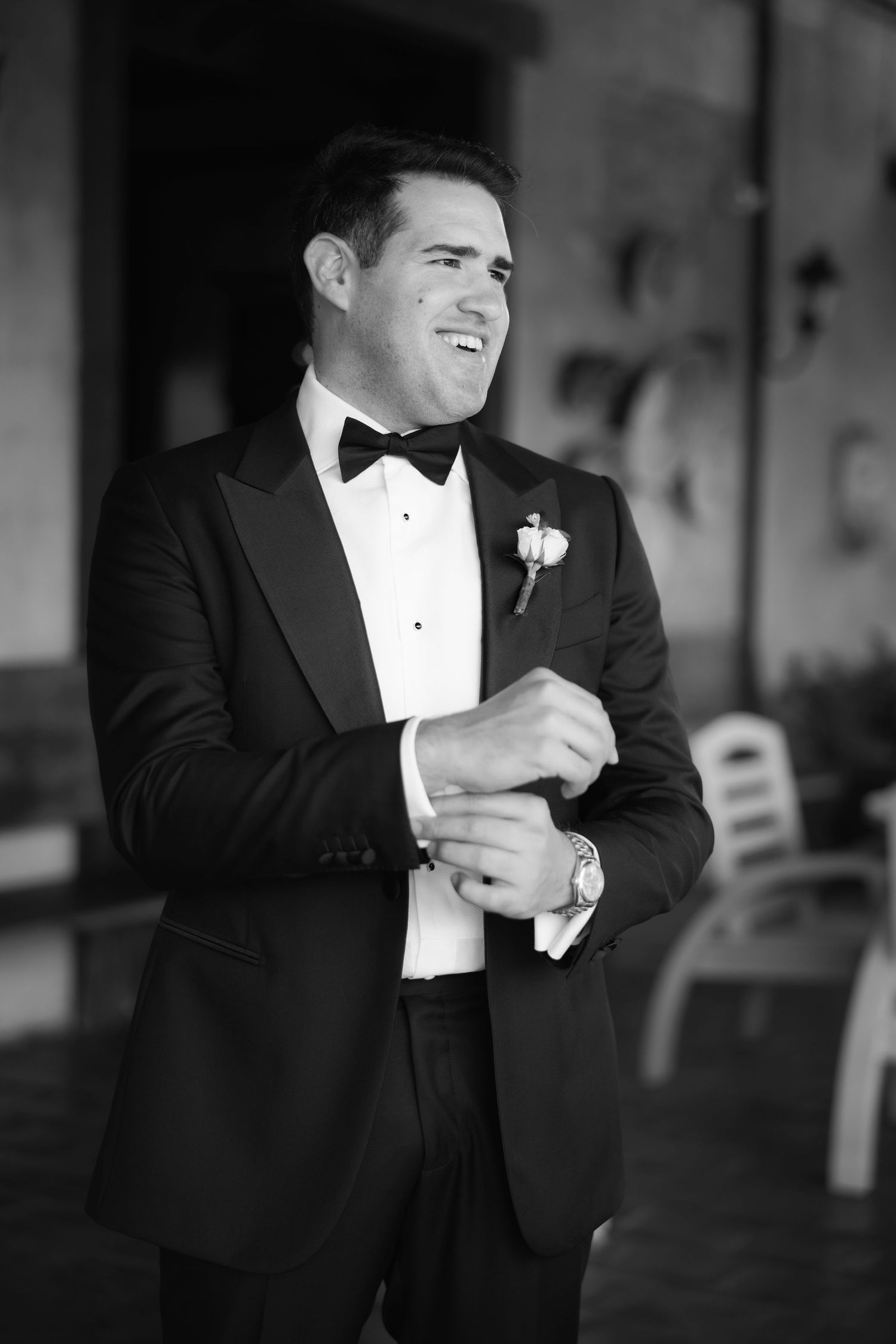 Black and white image of a groom in tuxedo preparing for his wedding day.