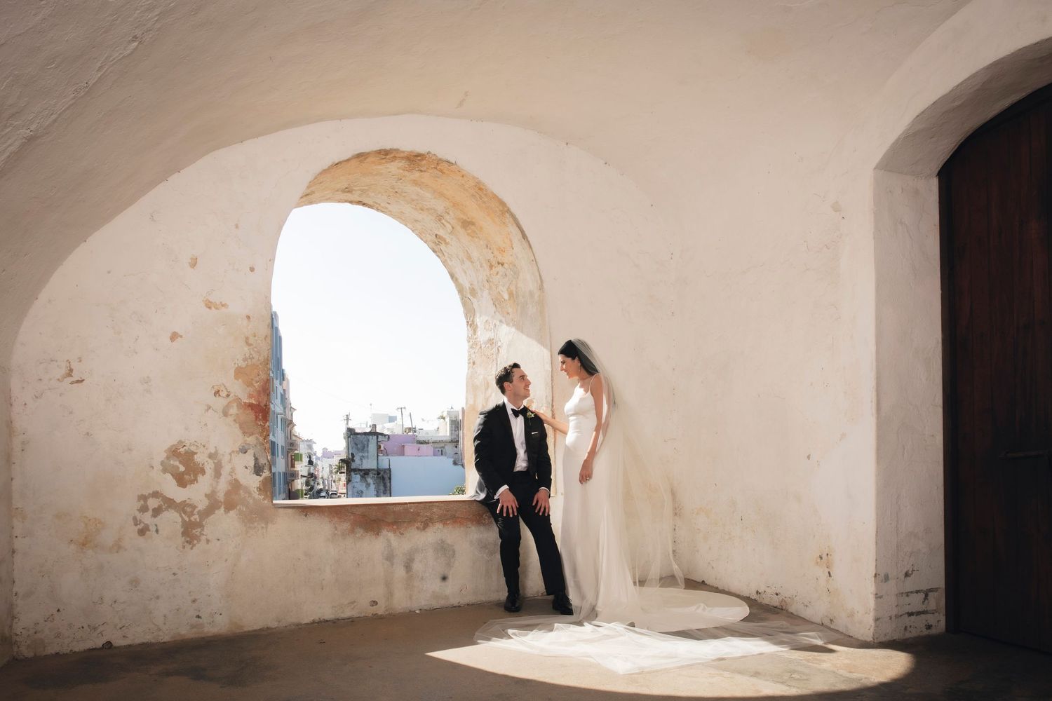 Panoramic view of empty white arched interior space with stone walls and curved ceiling features.