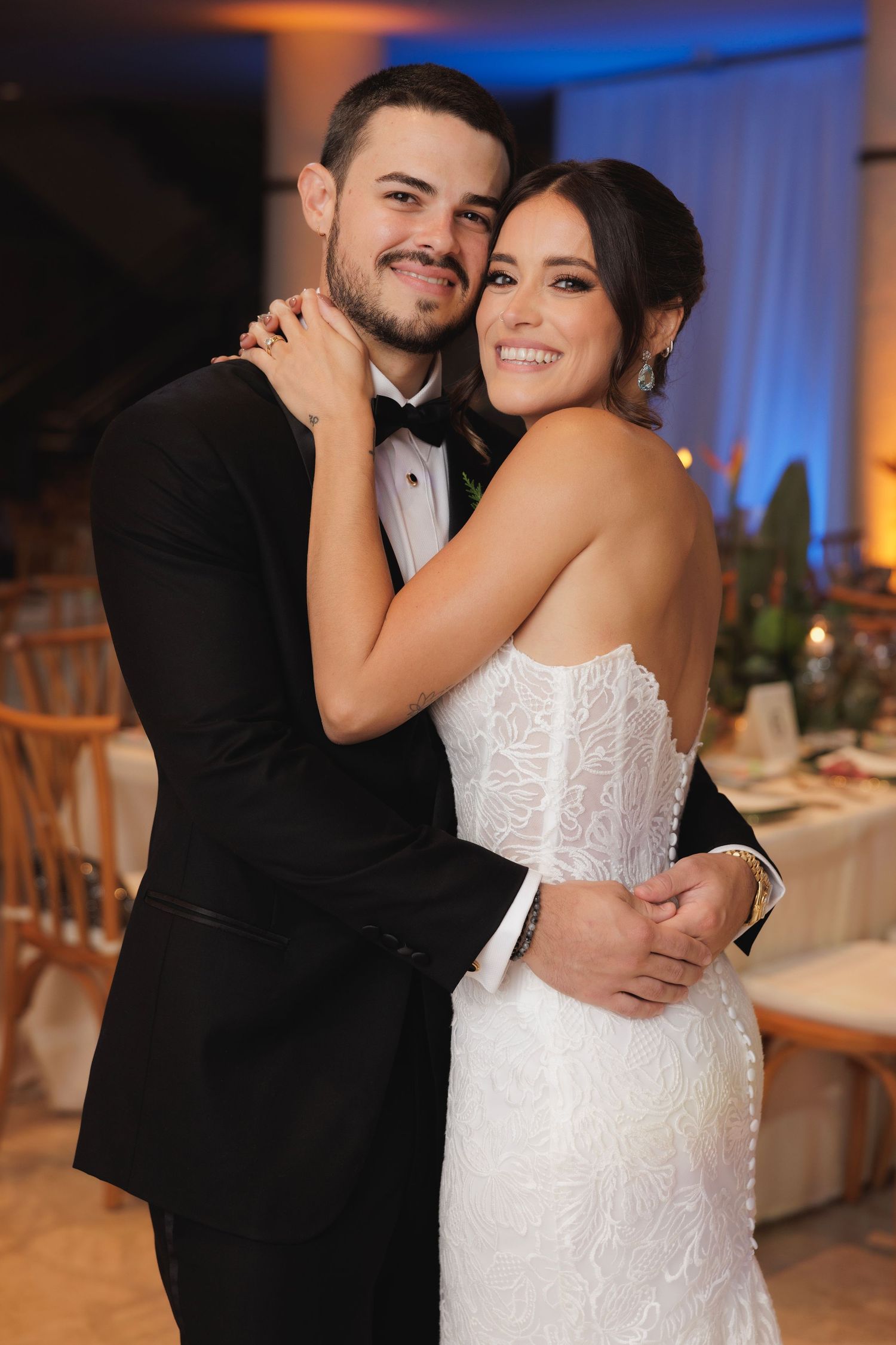 A newlywed couple shares intimate moments during their wedding reception in a beautifully lit venue.