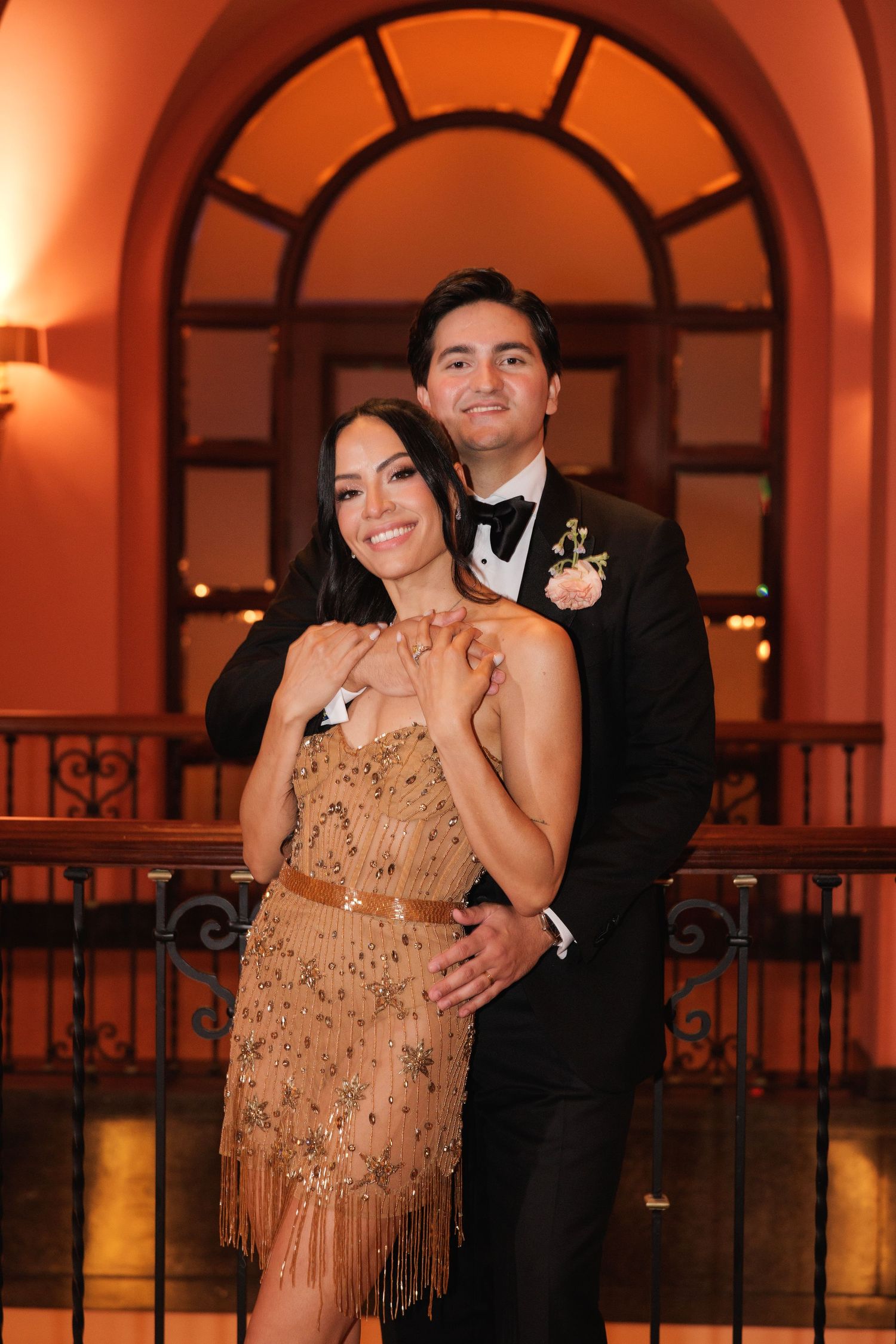 Romantic evening photo in an arched hallway with warm amber lighting and ornate architecture.