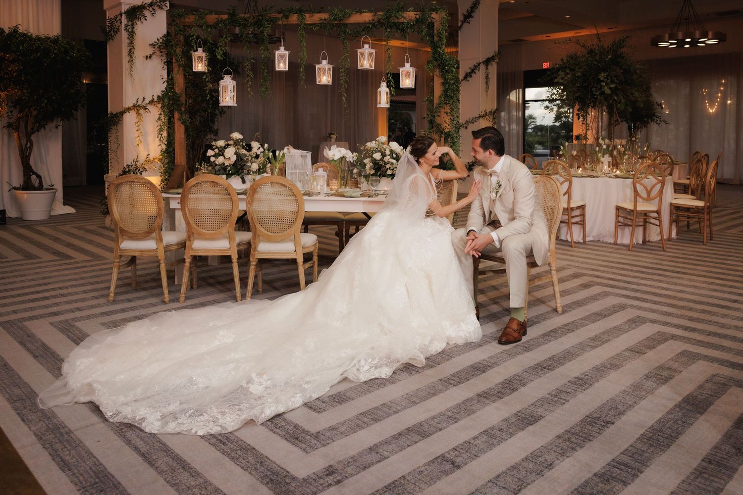 A wedding couple shares a romantic dance together on an elegant ballroom dance floor with ornate lighting.