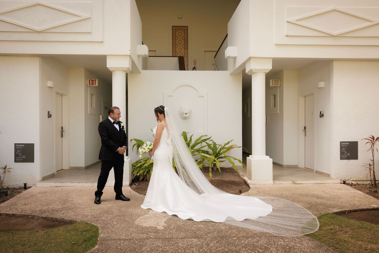 Wedding couple shares a romantic moment together in a classic white columned architectural setting.