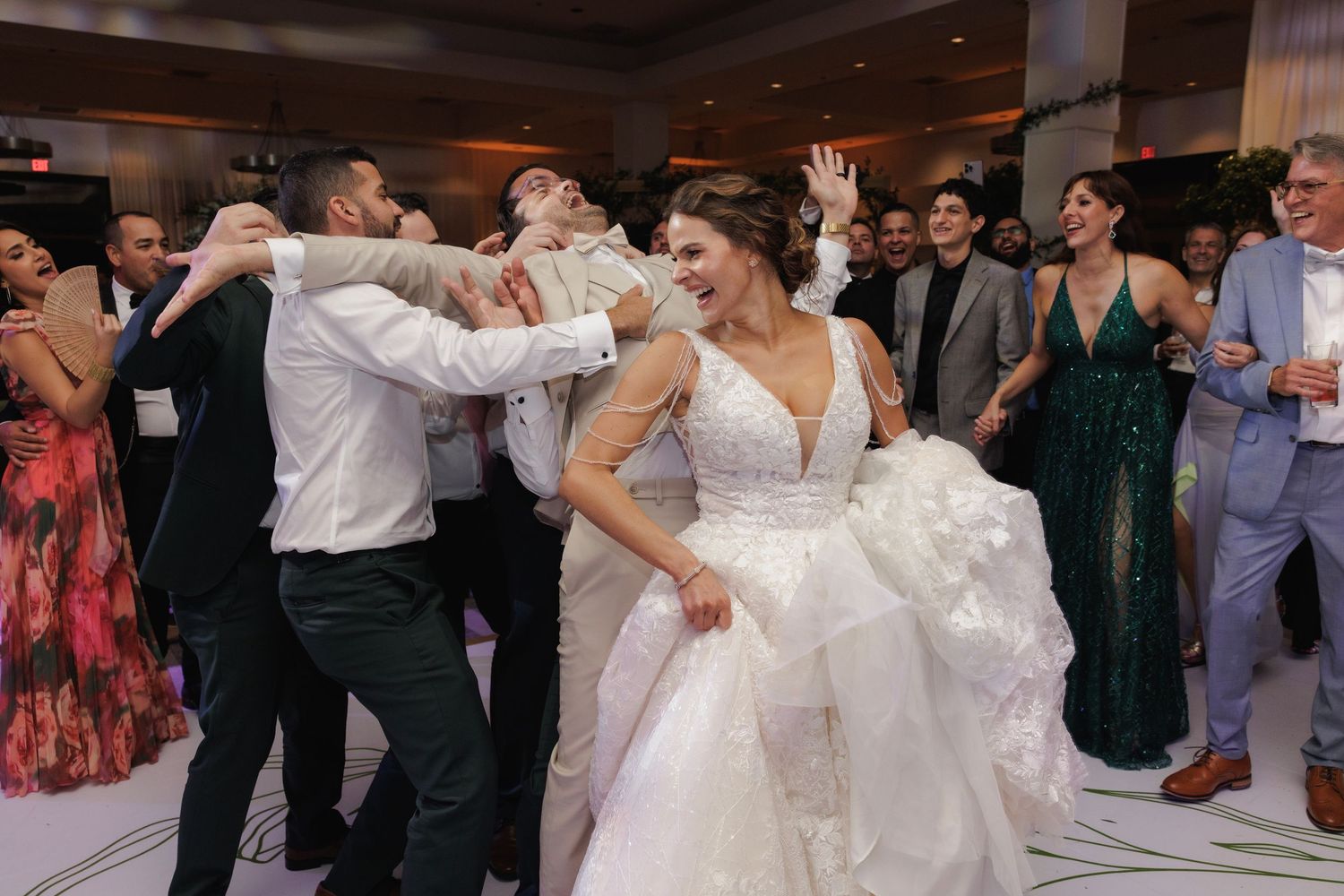 Wedding reception guests dancing and celebrating together on the dance floor during a festive evening celebration.