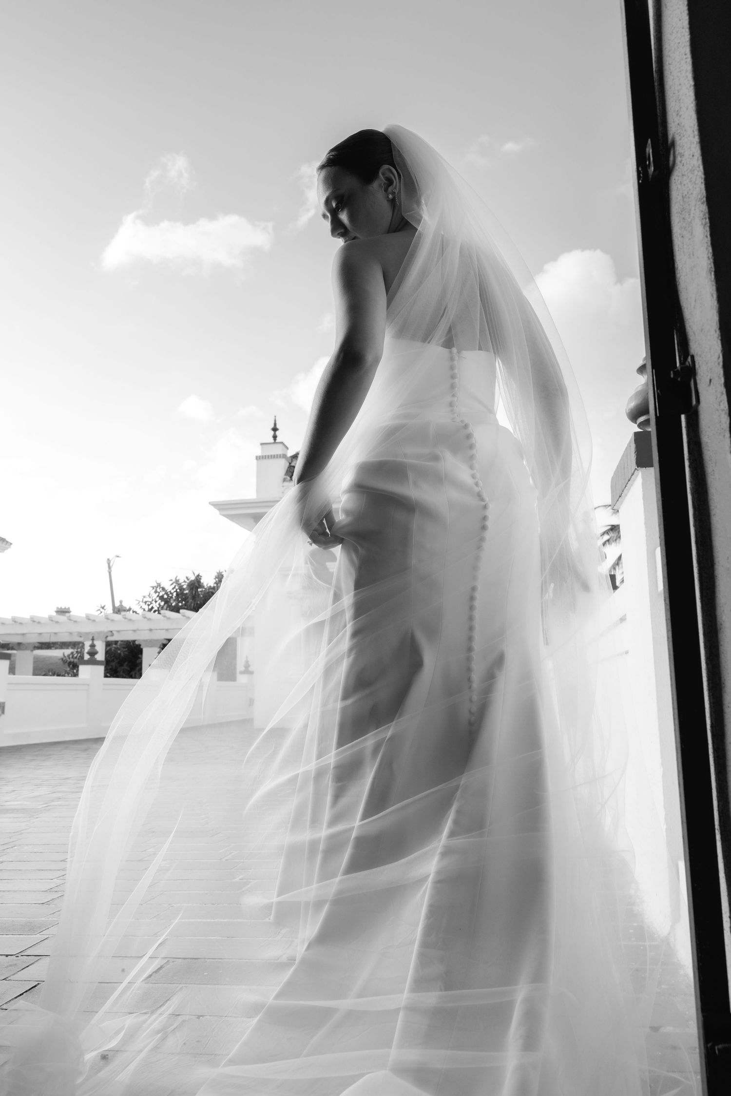 Flowing wedding veil catches sunlight against architectural backdrop in artistic sequence.