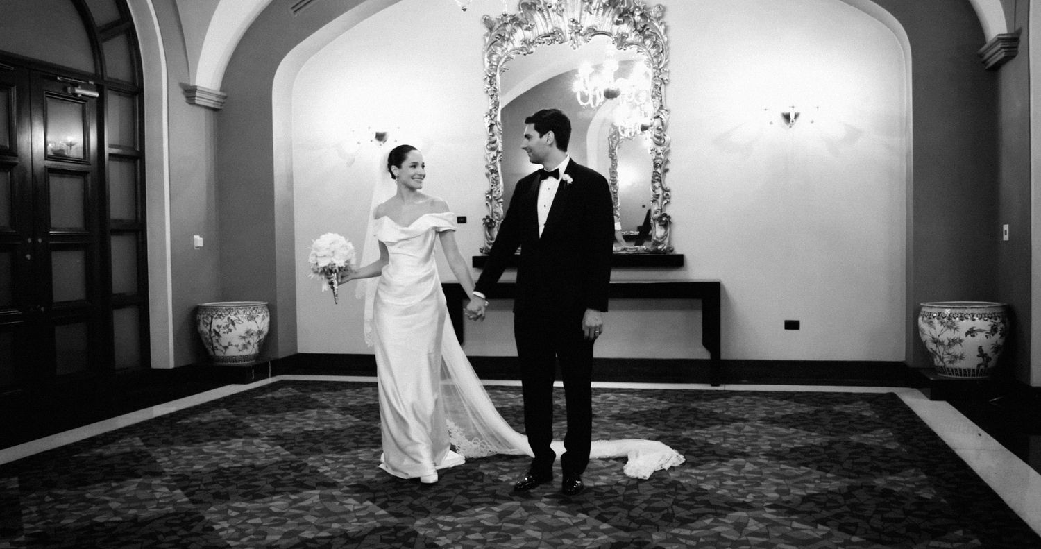 Wedding couple captured in elegant venue hallway with black and white photography effect.