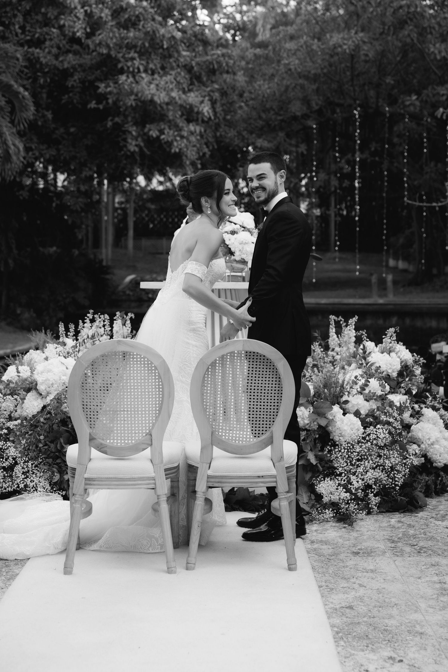 Black and white photos of newlyweds sharing romantic moments on vintage chairs in garden setting.
