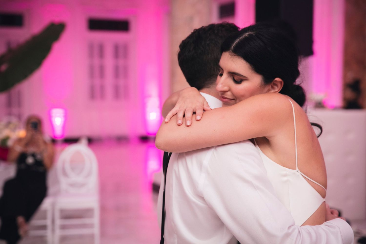 Dance floor illuminated with pink uplighting during a wedding celebration.