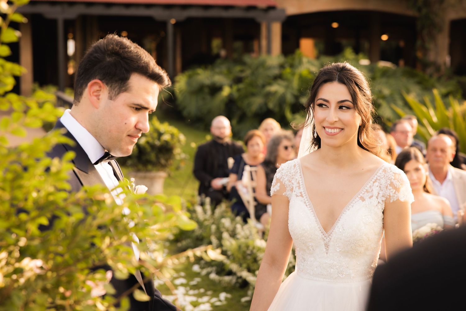 Outdoor wedding ceremony in lush garden setting with golden hour lighting.