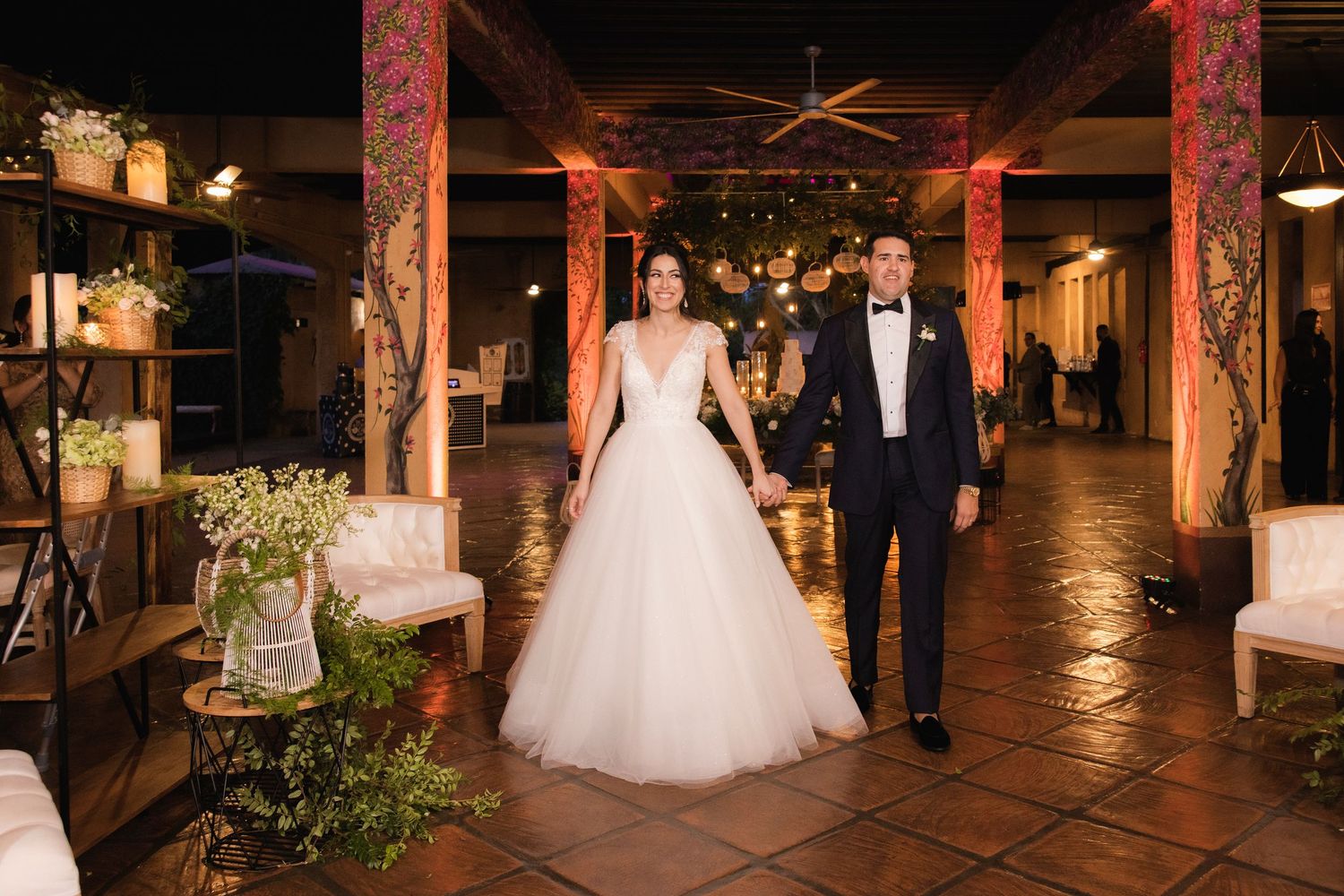 Wedding couple walking through rustic venue with warm ambient lighting and wooden beams.
