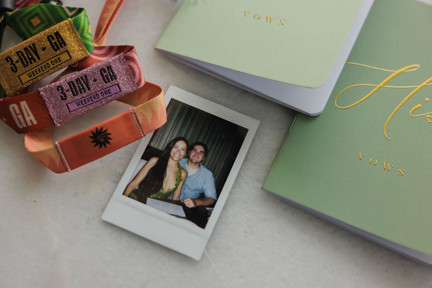 Wedding stationery and polaroid photo arranged with pink and green decorative elements.