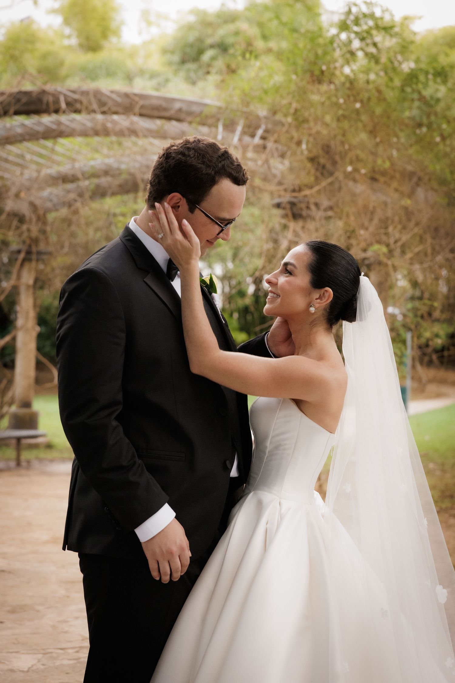 Romantic outdoor wedding portraits on a garden path surrounded by trees.
