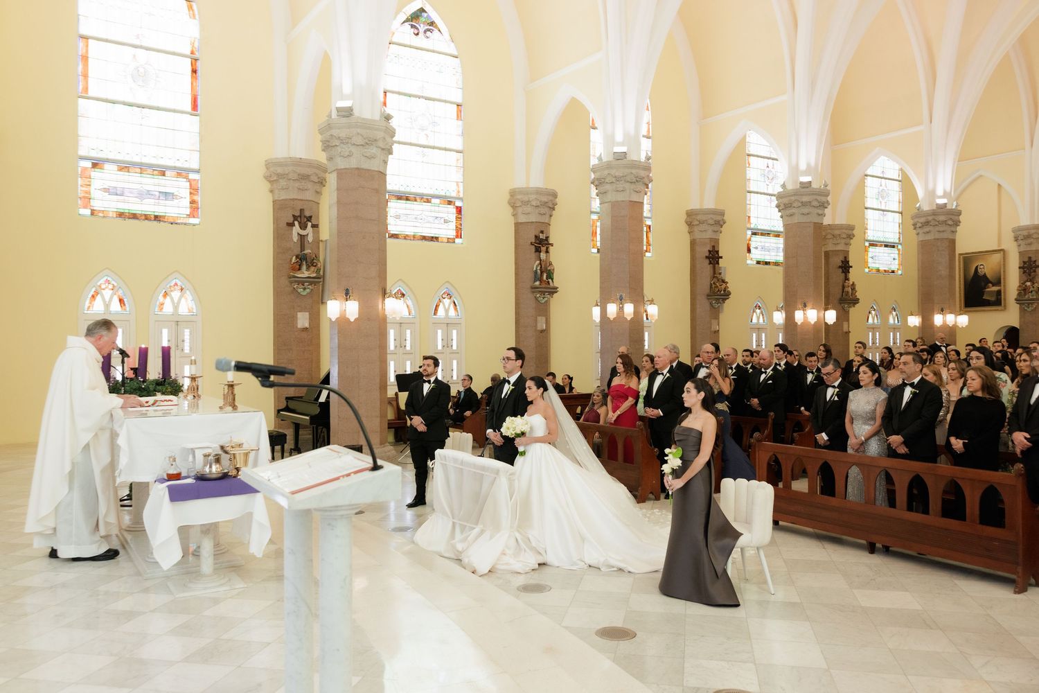 A traditional church wedding ceremony takes place in a grand cathedral with high arched ceilings and stained glass windows.