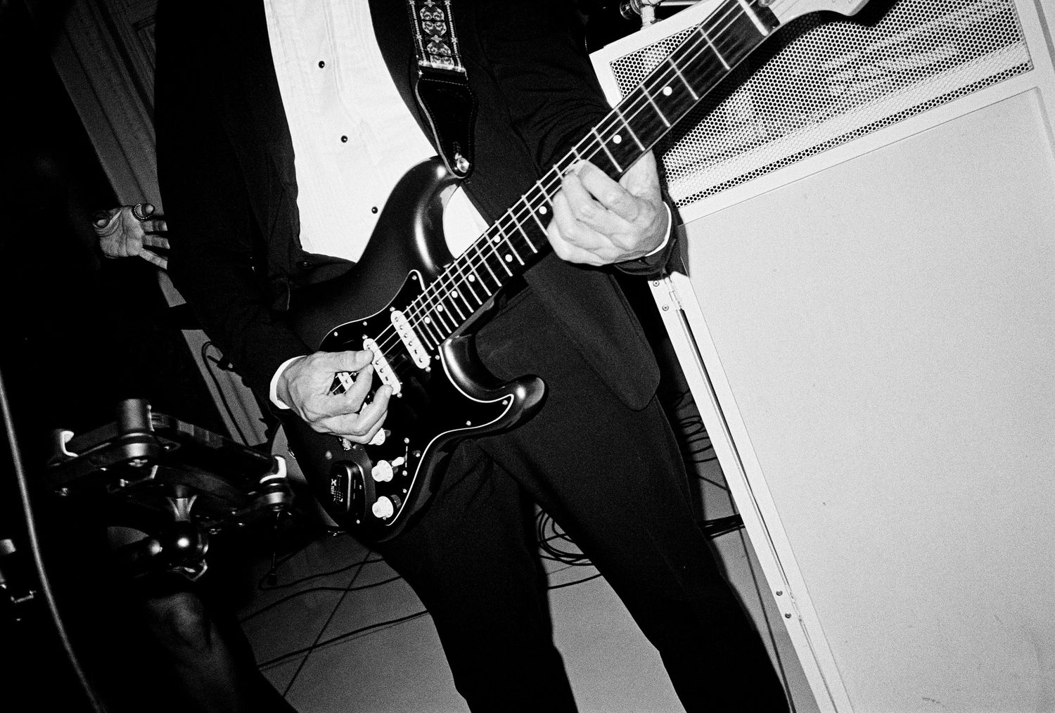Black and white photo of a guitarist playing an electric guitar on stage during a live performance.