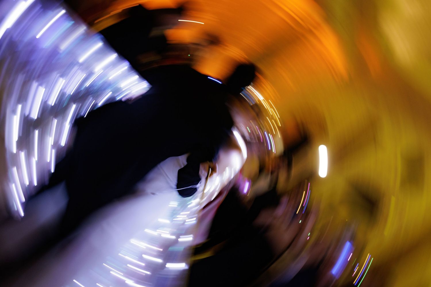 Abstract light trails creating swirling patterns in purple and gold tones against a dark background.