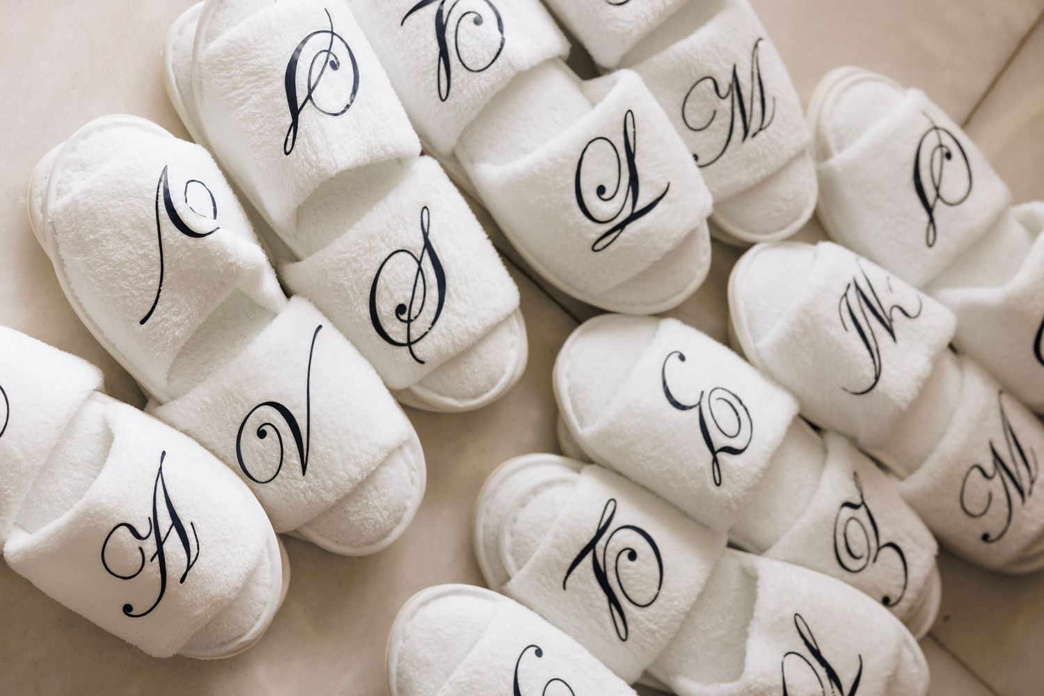 White silk robes with monogrammed initials hanging in a row on wooden hangers.