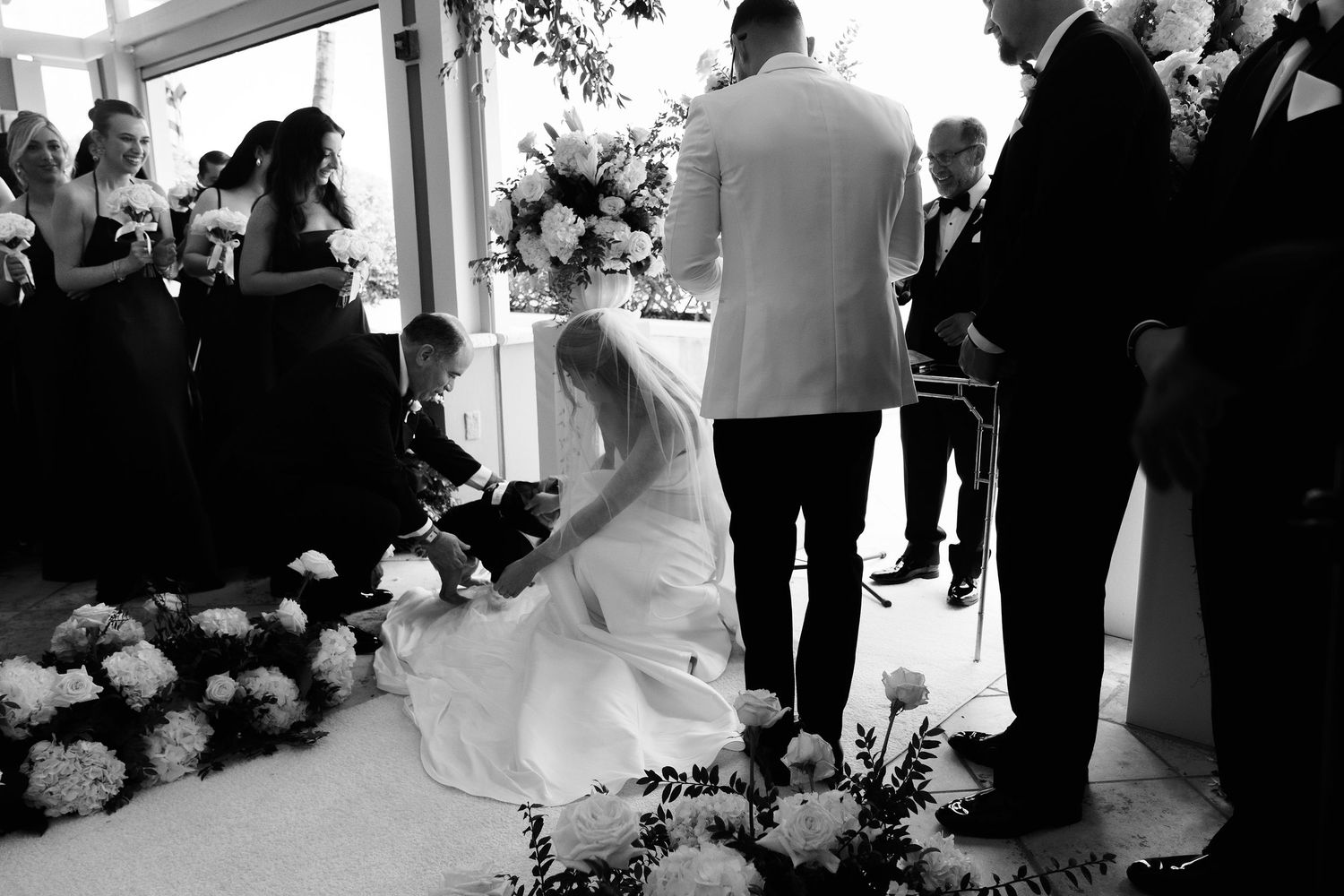 Black and white candid wedding ceremony moment with floral decorations.