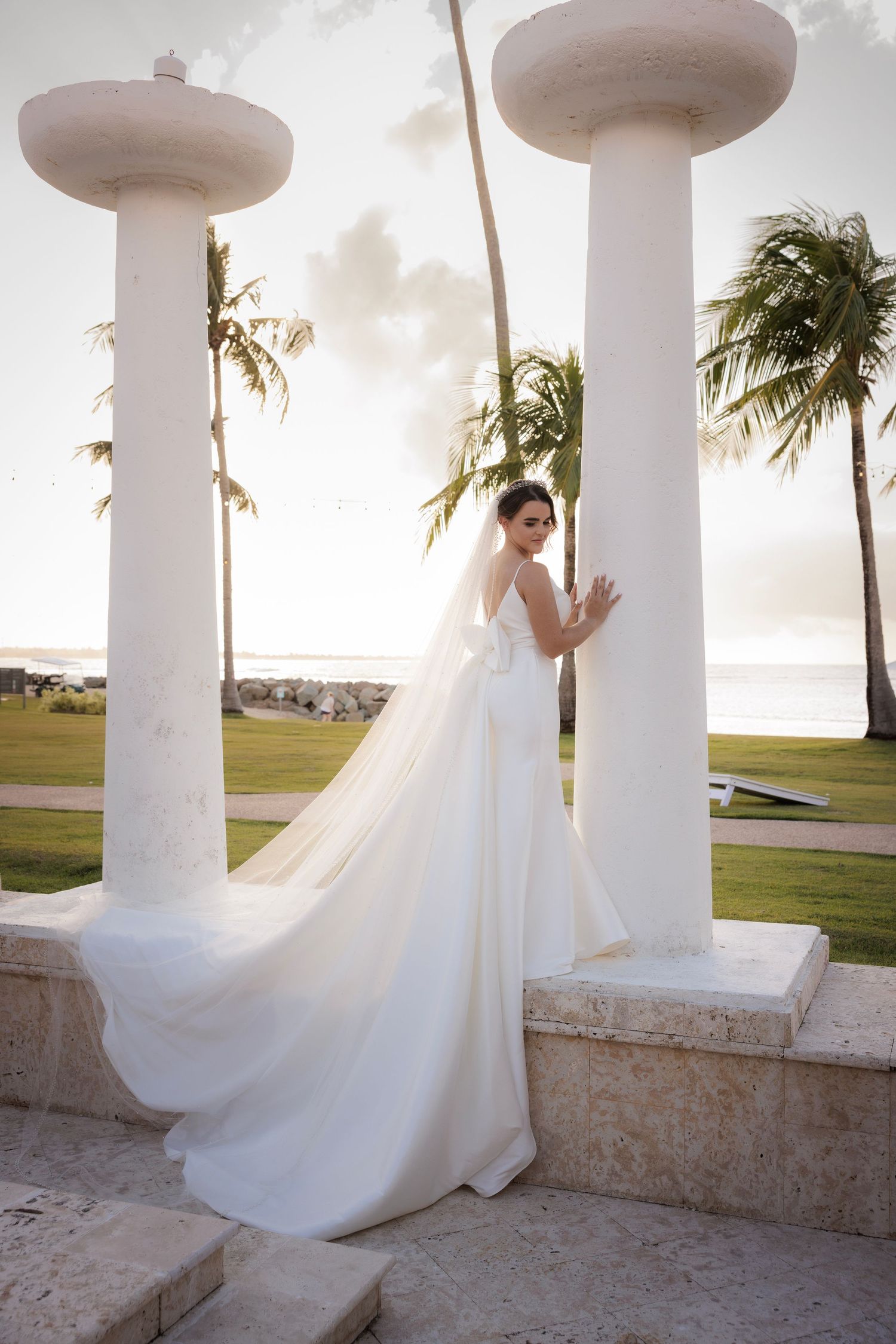 A sequence of elegant bridal photos showing flowing white wedding dress movement between white columns at sunset.