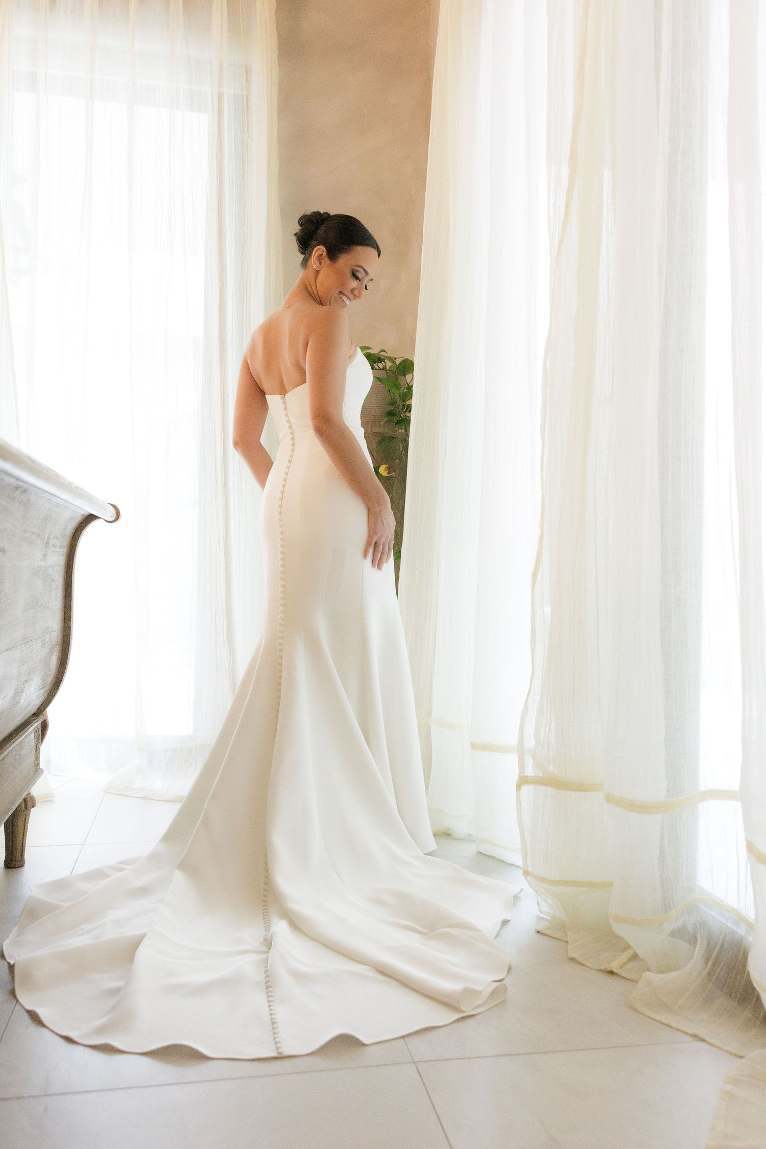 Flowing white wedding dress photographed in sequence against sunlit windows.