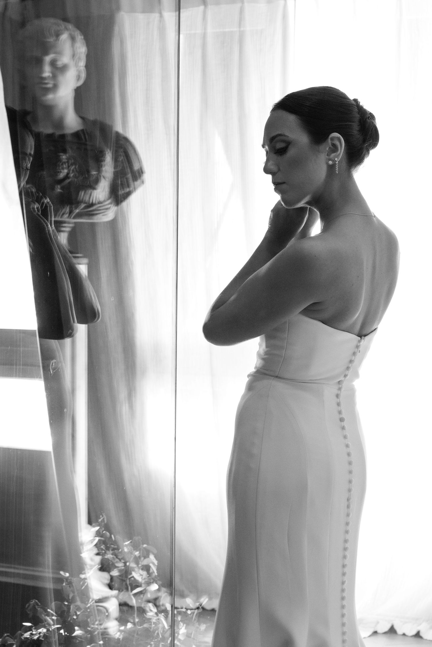 A monochromatic bridal portrait showing multiple angles of an elegant wedding dress with buttons down the back.