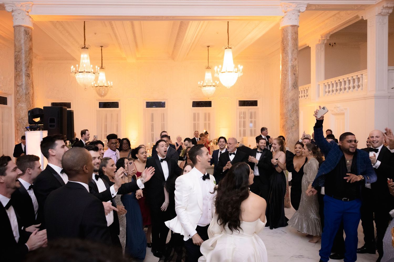 Elegant ballroom filled with wedding guests dancing and celebrating at an upscale reception venue.