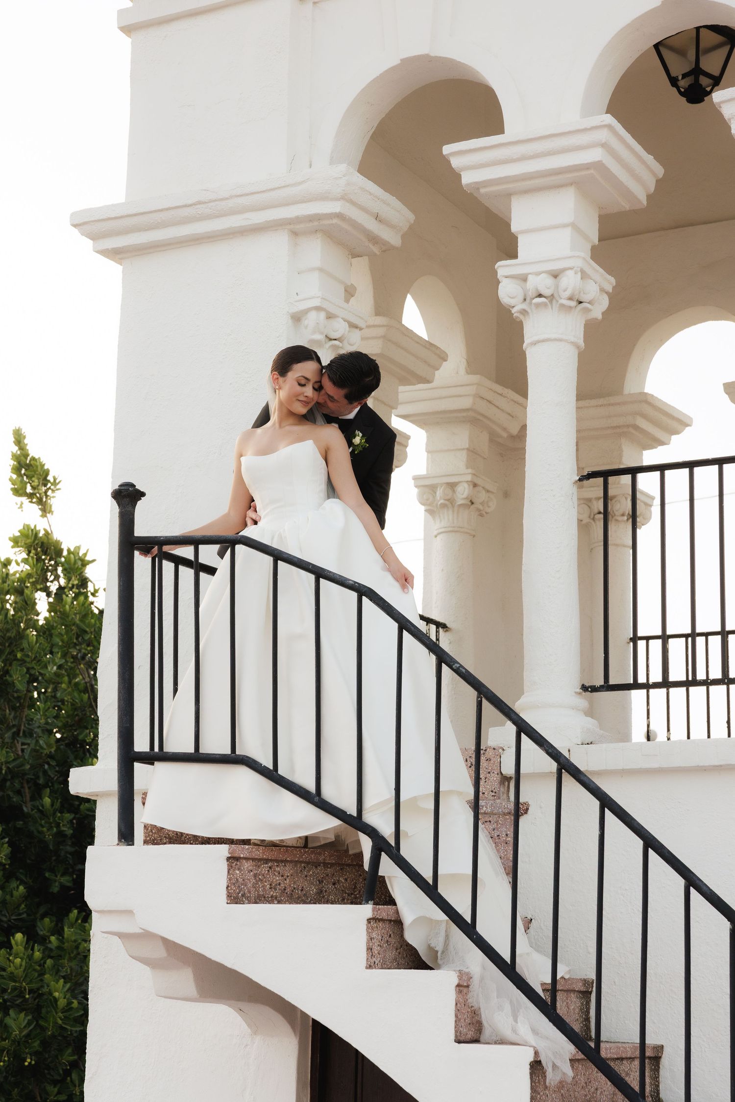 A romantic sequence of wedding photos showing a couple embracing on white stone steps with elegant archways.
