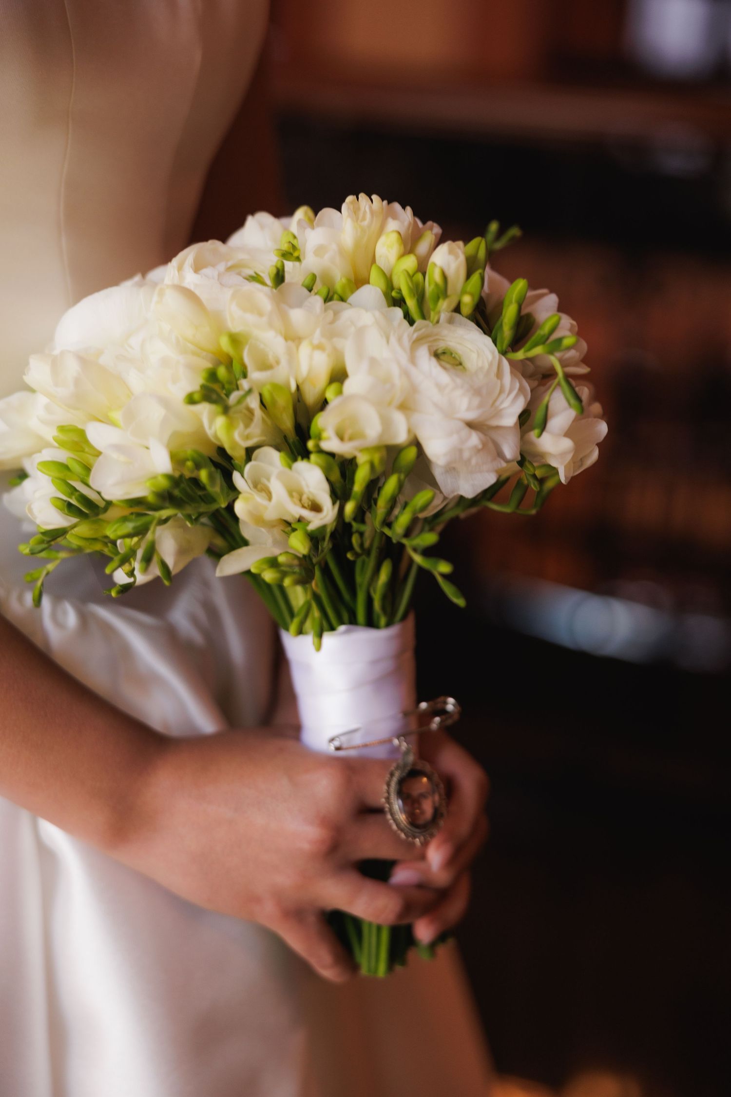 A delicate white freesia bouquet with green foliage arranged in a classic wedding style.