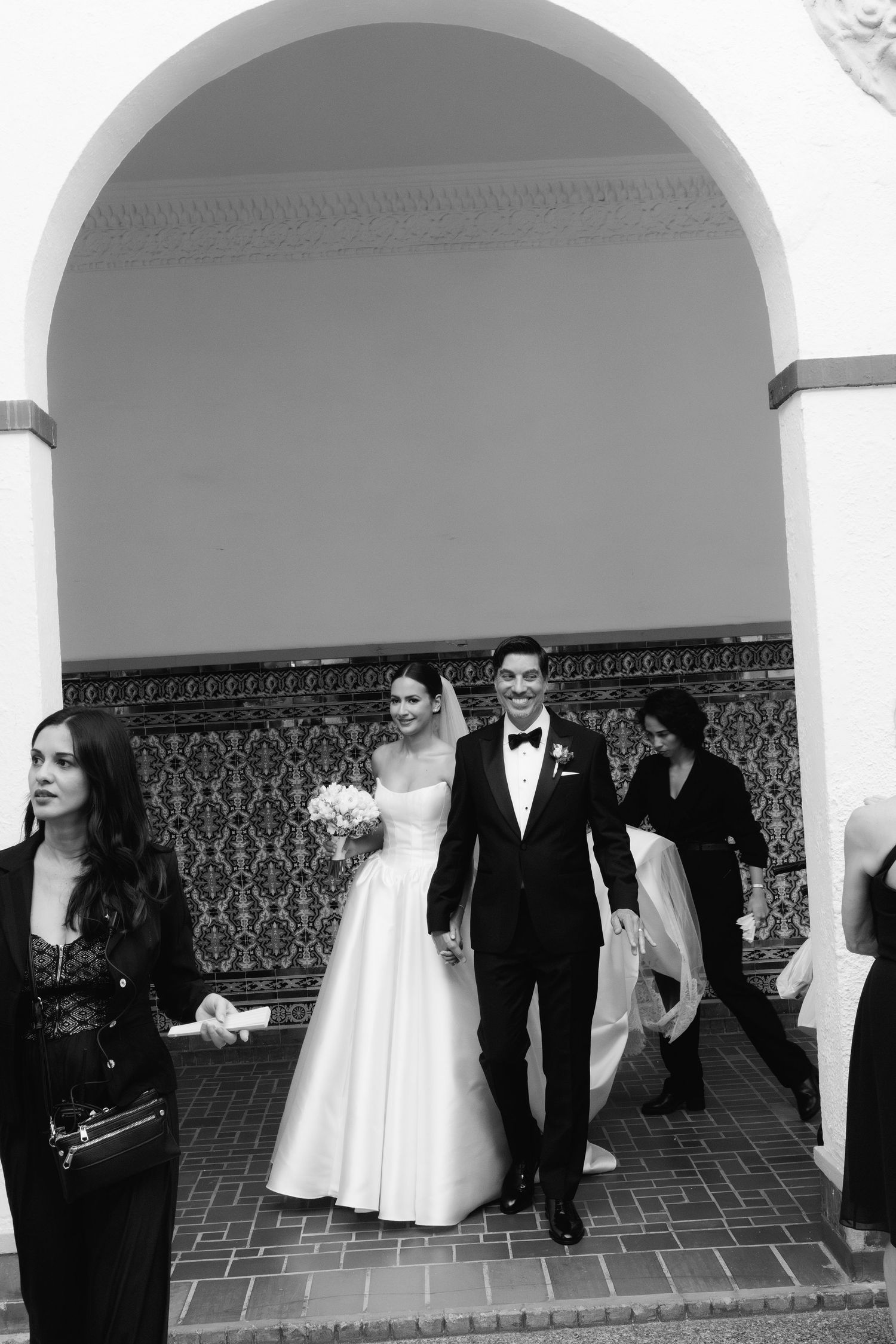 Black and white wedding photos showing guests and couple in an elegant columned courtyard.