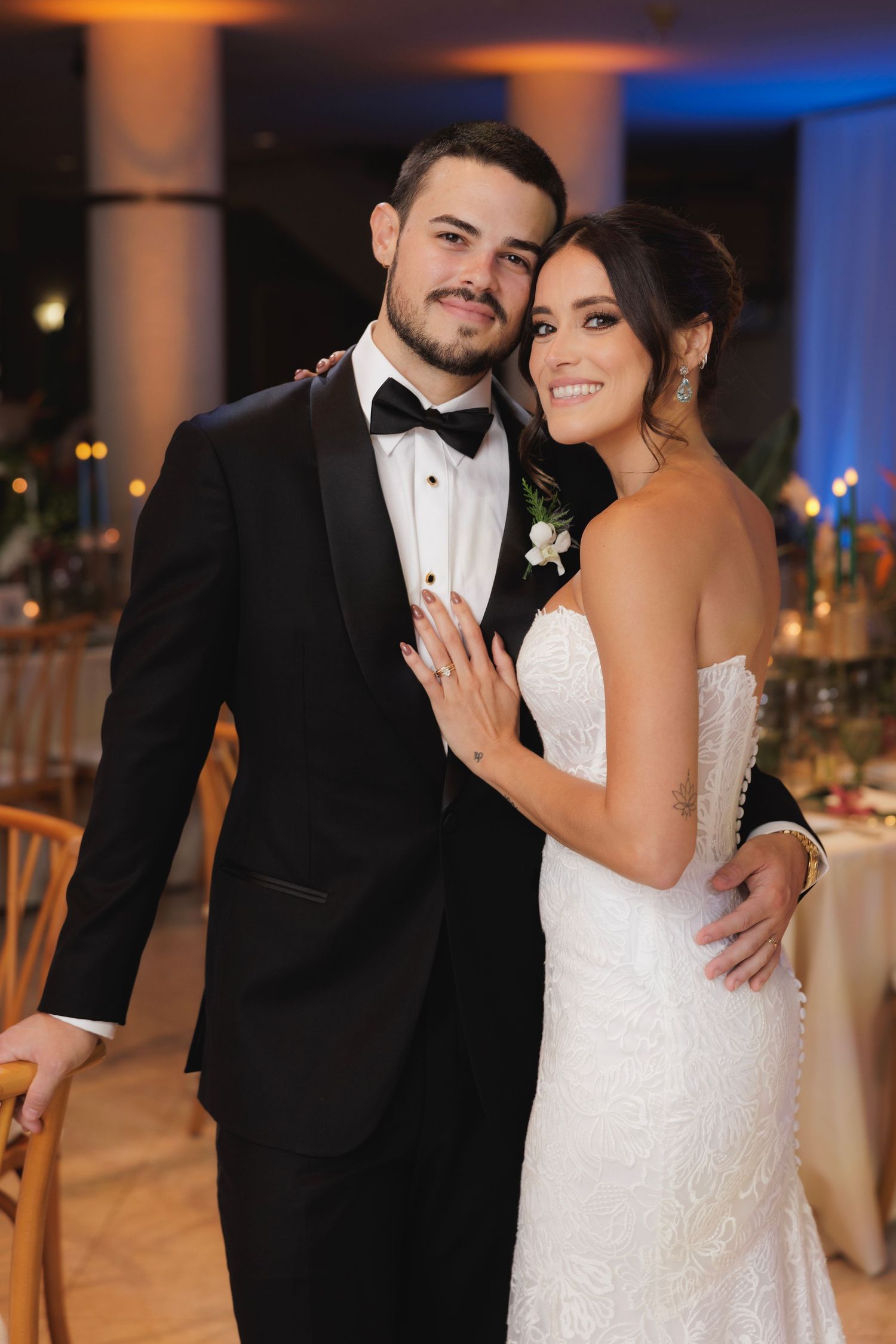 Romantic wedding reception moment captured in an elegantly lit ballroom with ambient blue and orange lighting.