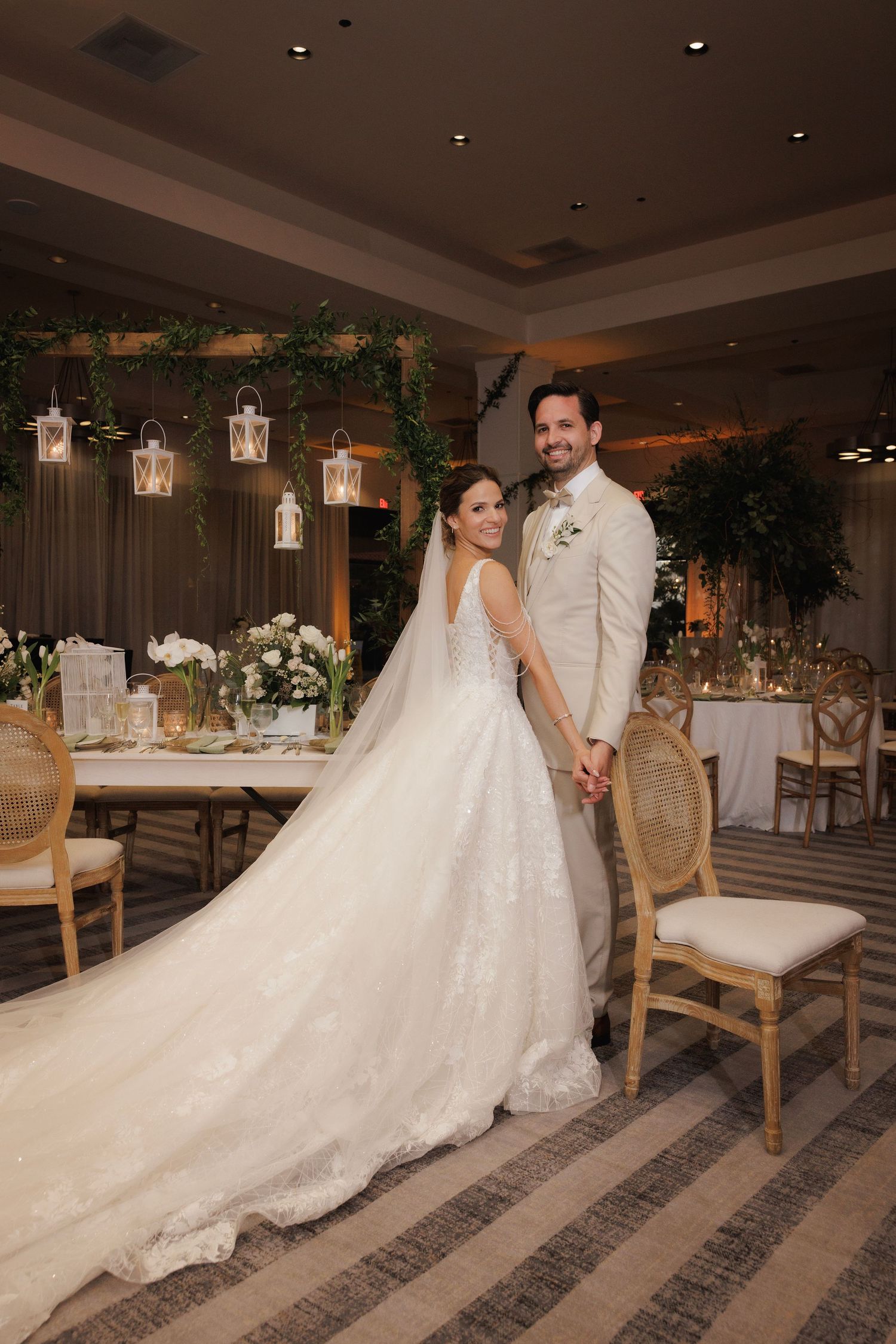 Dancing couple twirling on a patterned floor at an elegantly decorated wedding reception venue with hanging lanterns.