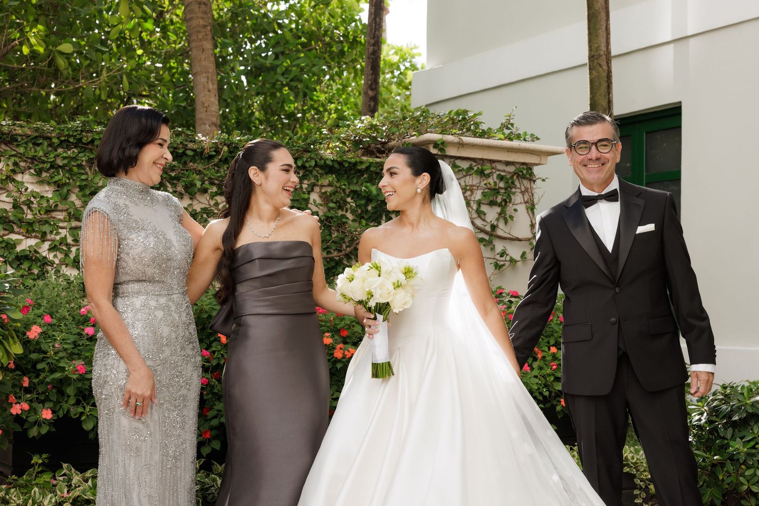 Wedding party members in formal attire gather outdoors for celebratory photos.