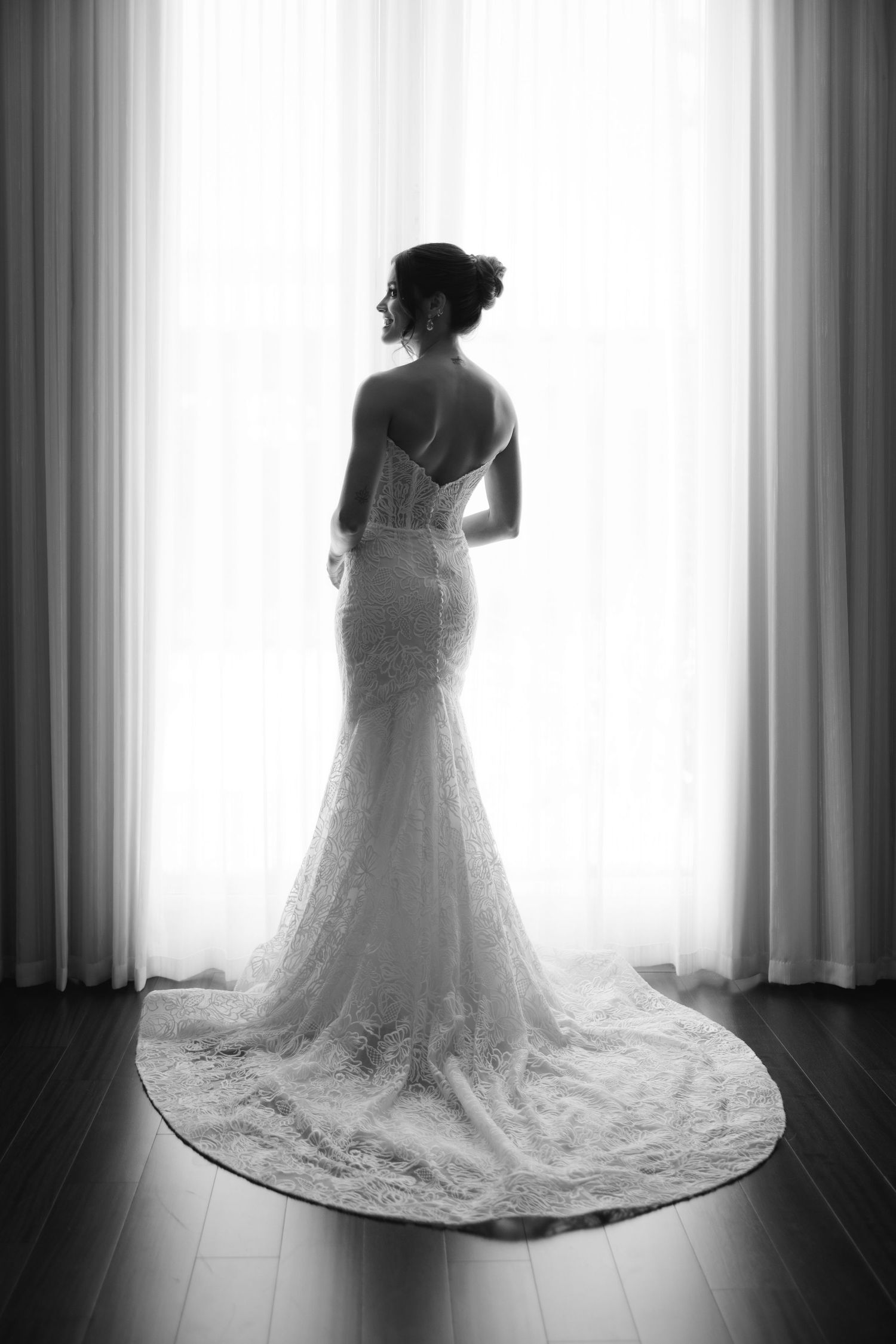Artistic black and white series showing the elegant train of a lace wedding dress against a window.