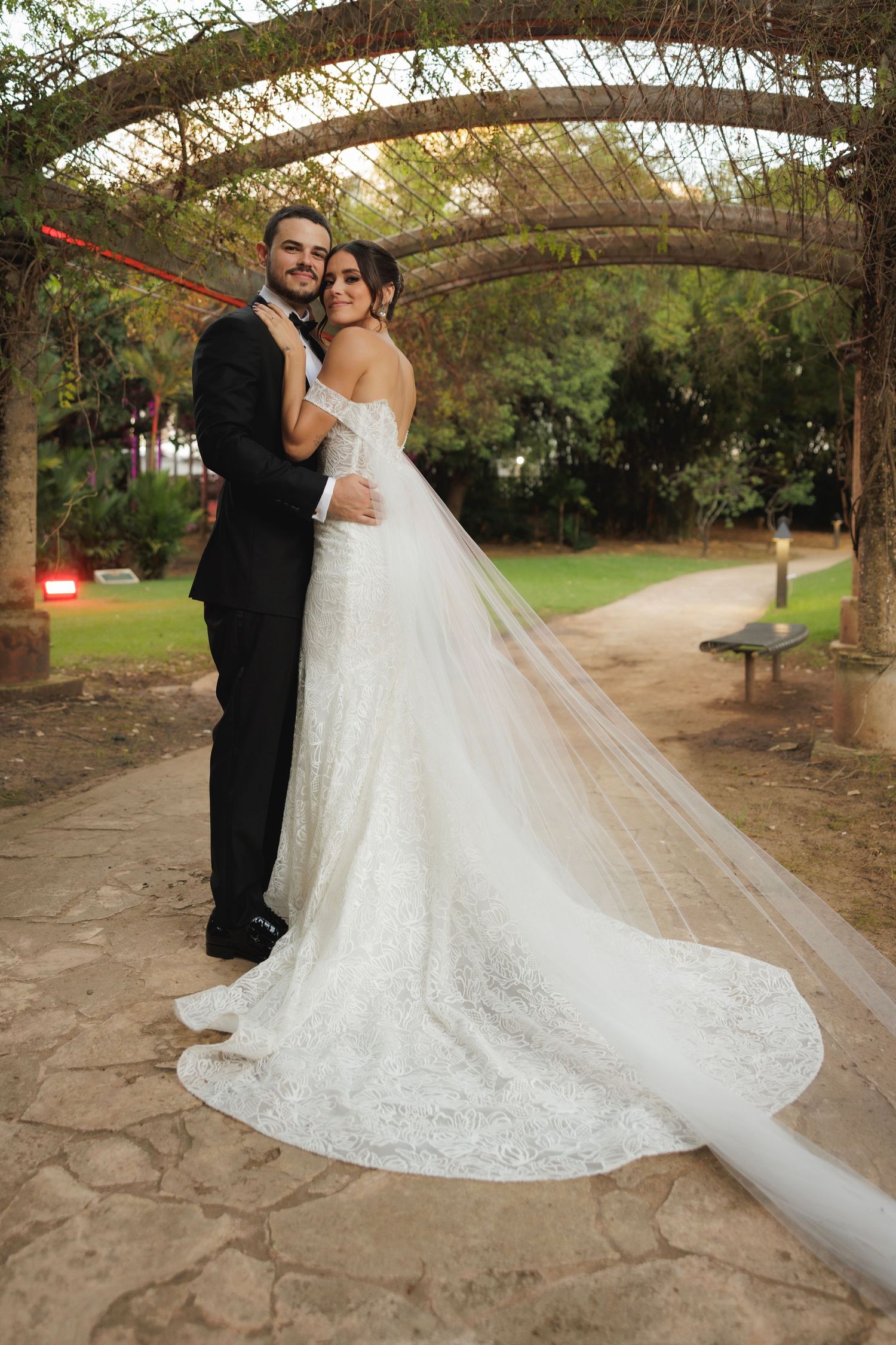 A series of wedding photos capturing intimate moments between newlyweds under a wooden arbor with flowing white veil.