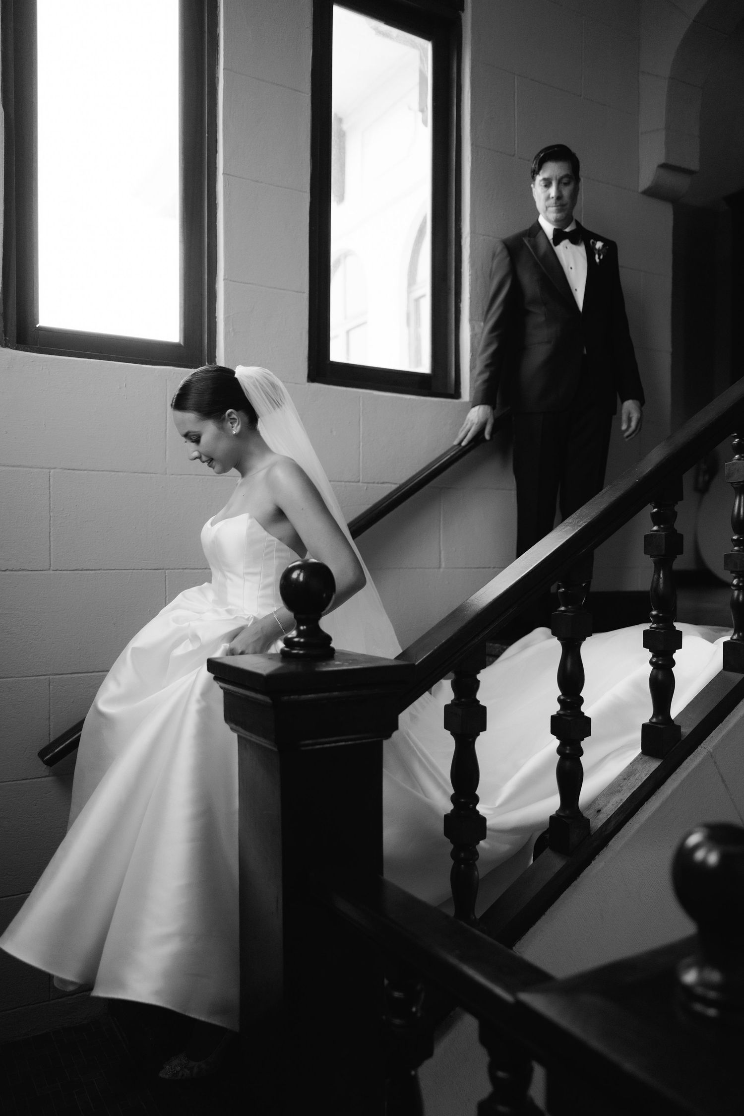 A series of black and white photos showing a bride in a white dress sitting on elegant wooden stairs.