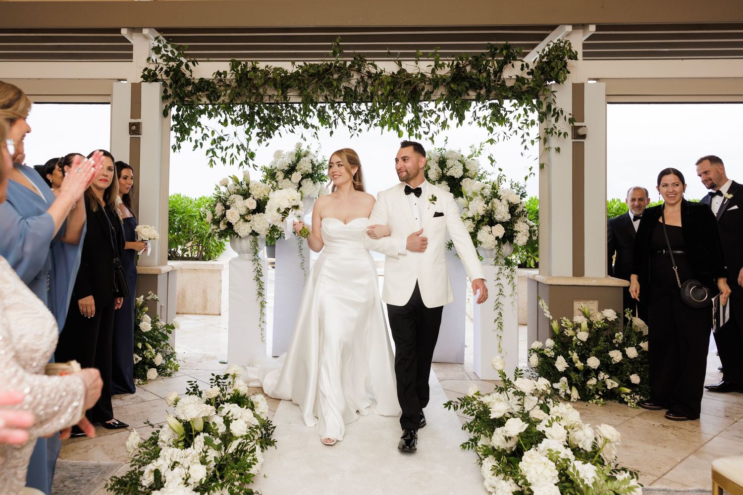Wedding ceremony and reception venue decorated with white floral arrangements and greenery.