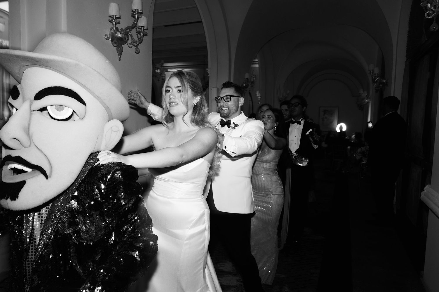 People dancing and celebrating at a lively party with theatrical masks and dramatic lighting.