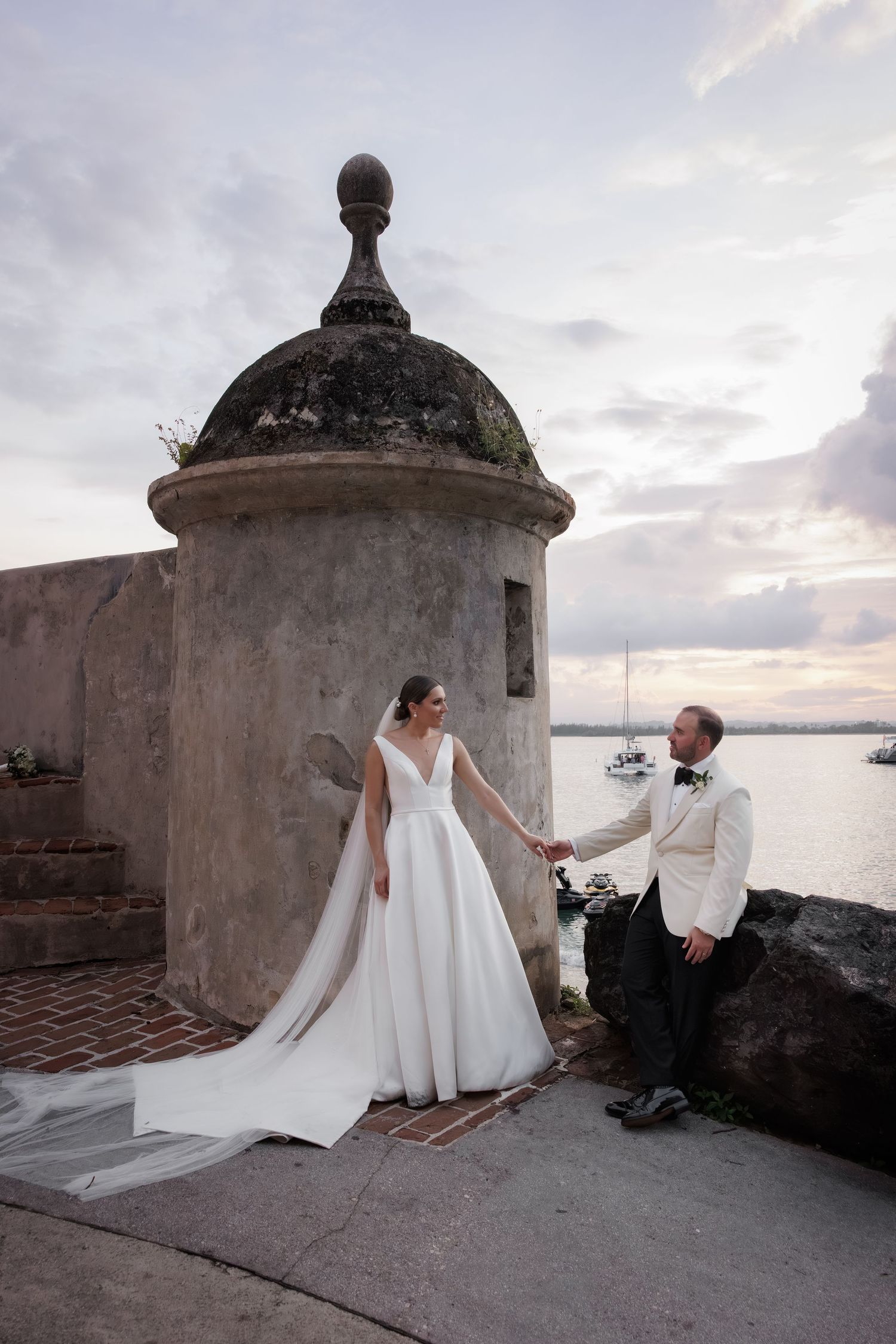 Romantic wedding photo session at sunset by historic stone fortification walls overlooking the ocean.