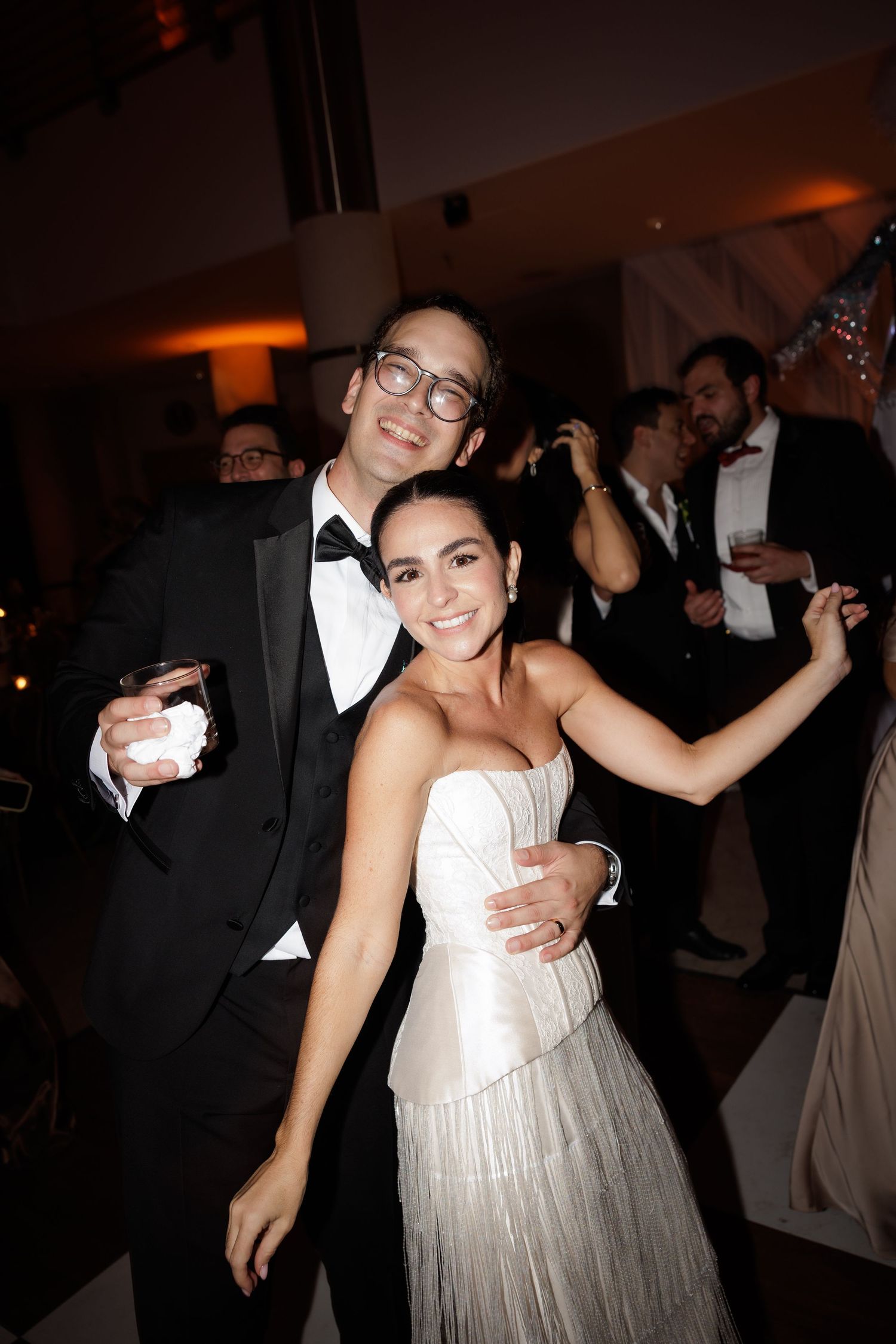 A couple celebrates on the dance floor at their wedding reception in formal attire.