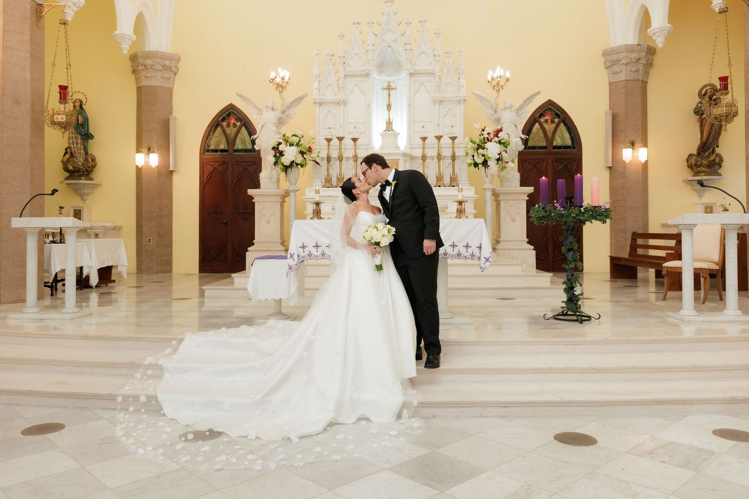 Wide angle view of wedding ceremony in yellow-walled church with classic architecture.