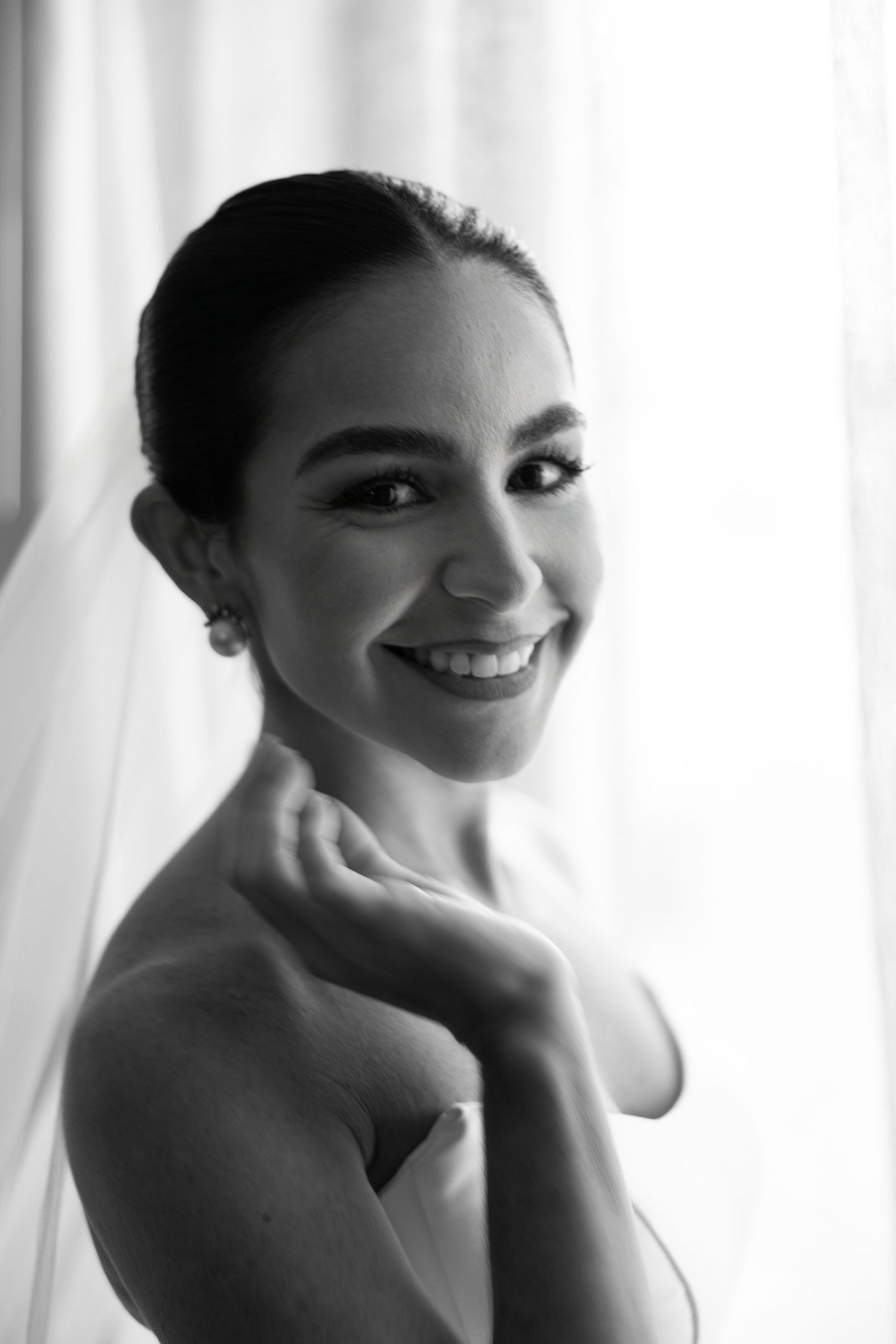 Black and white portraits of a bride smiling through a sheer veil on her wedding day.