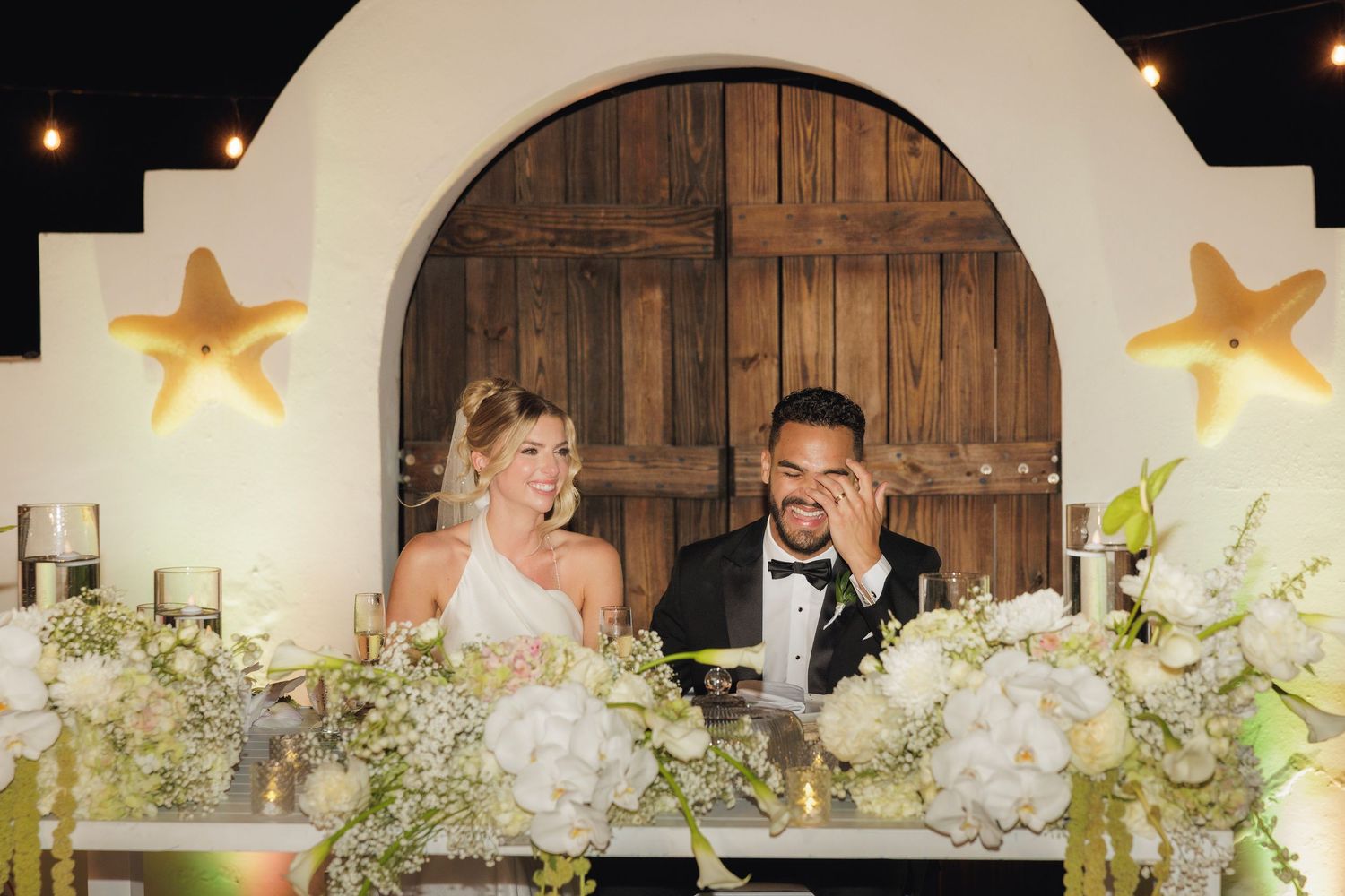 A wedding reception hall decorated with illuminated stars and rustic wooden doors creates a cozy romantic atmosphere.