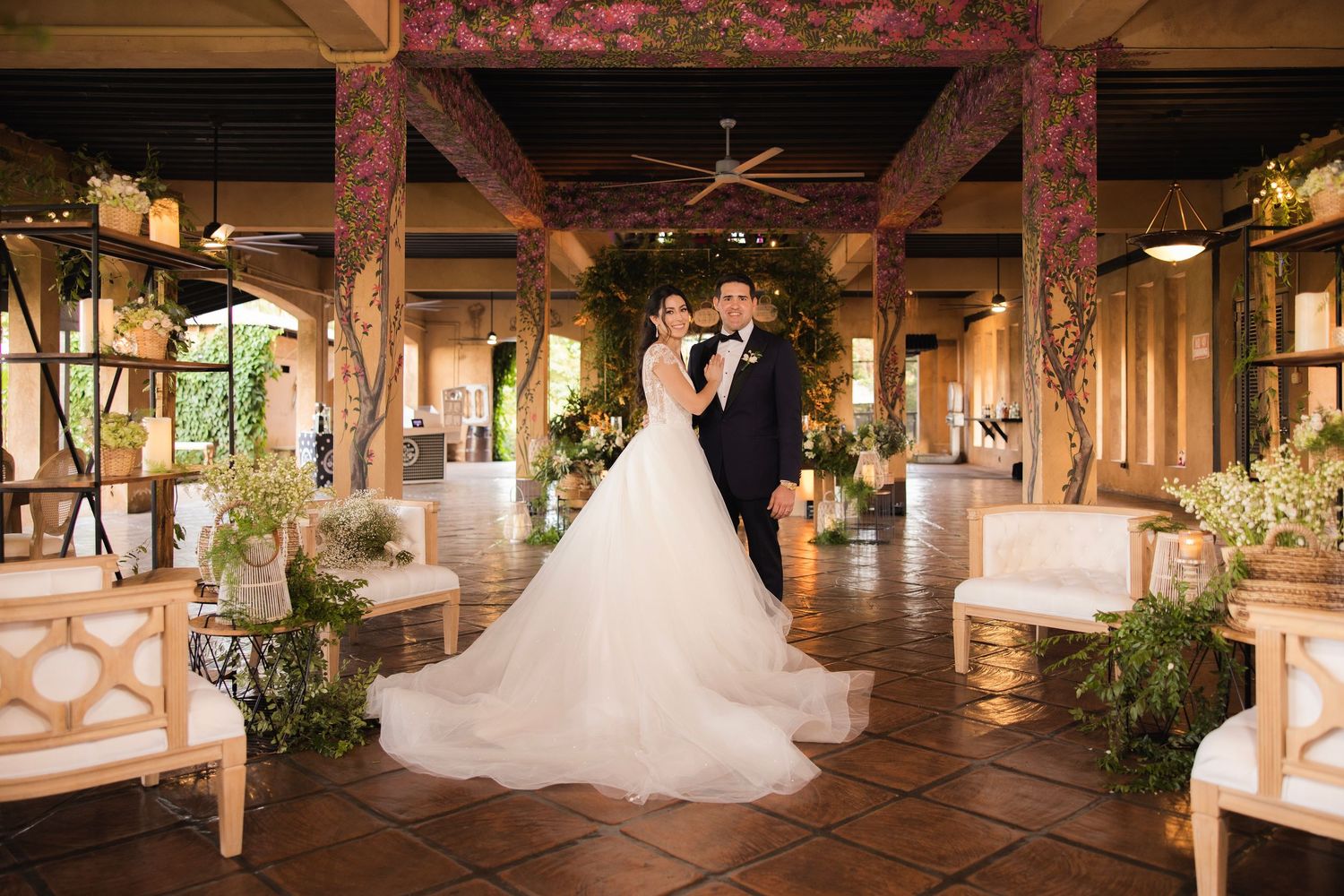 A romantic wedding scene inside a rustic barn venue decorated with string lights and floral arrangements.