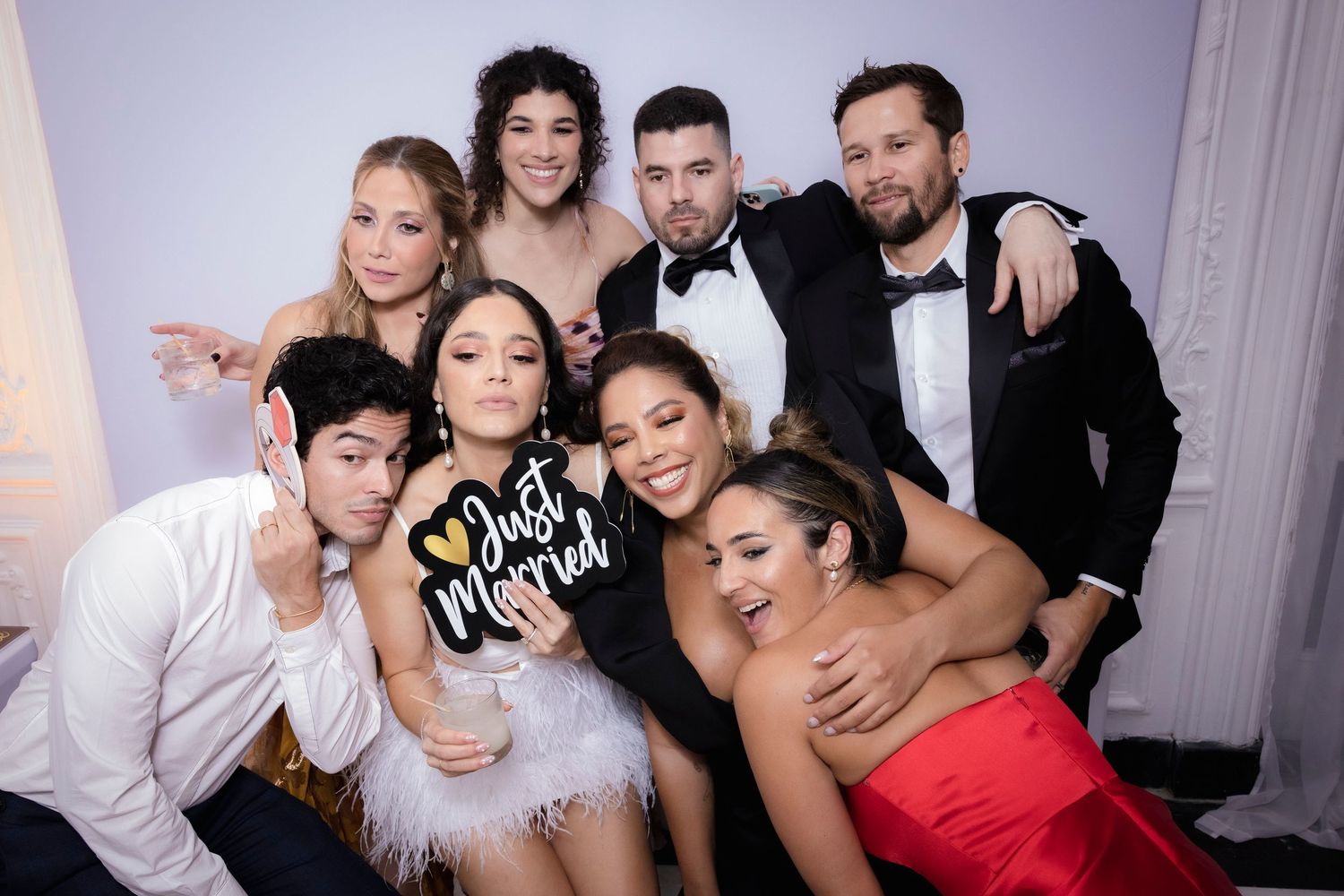 Group of fashionably dressed party guests posing together at an elegant celebration.