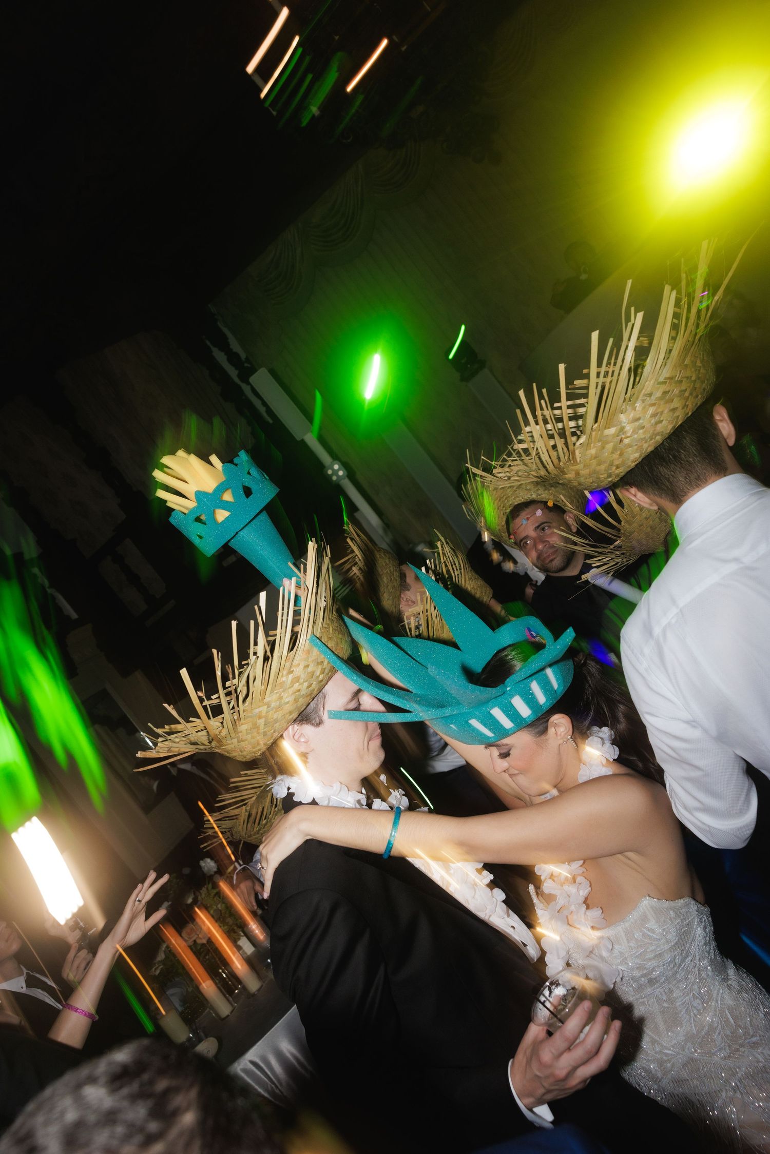 Wedding guests dance and celebrate with bright neon lighting effects at a lively reception party.