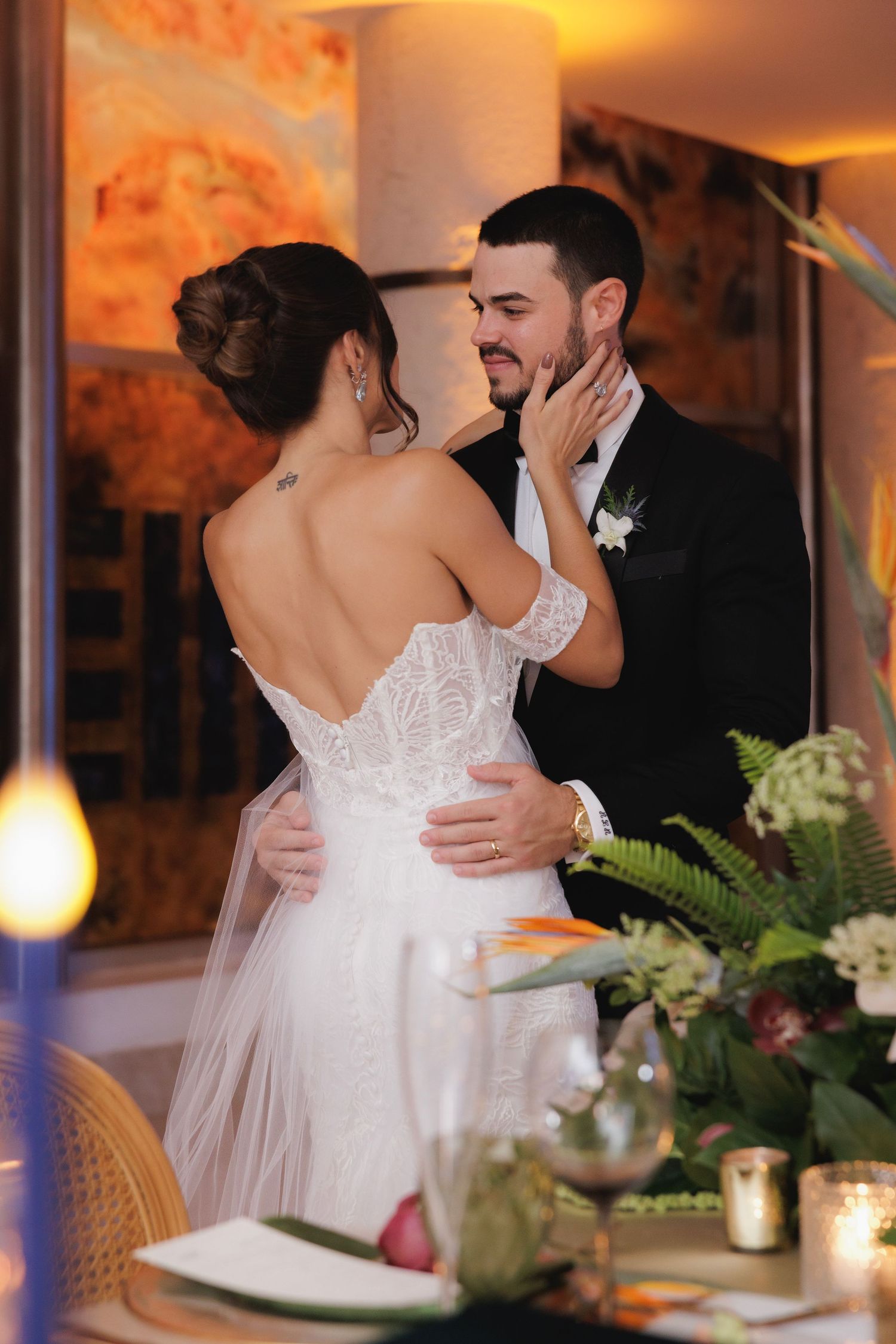 Romantic moment between newlyweds sharing an intimate dance at their wedding reception with floral decor and warm lighting.