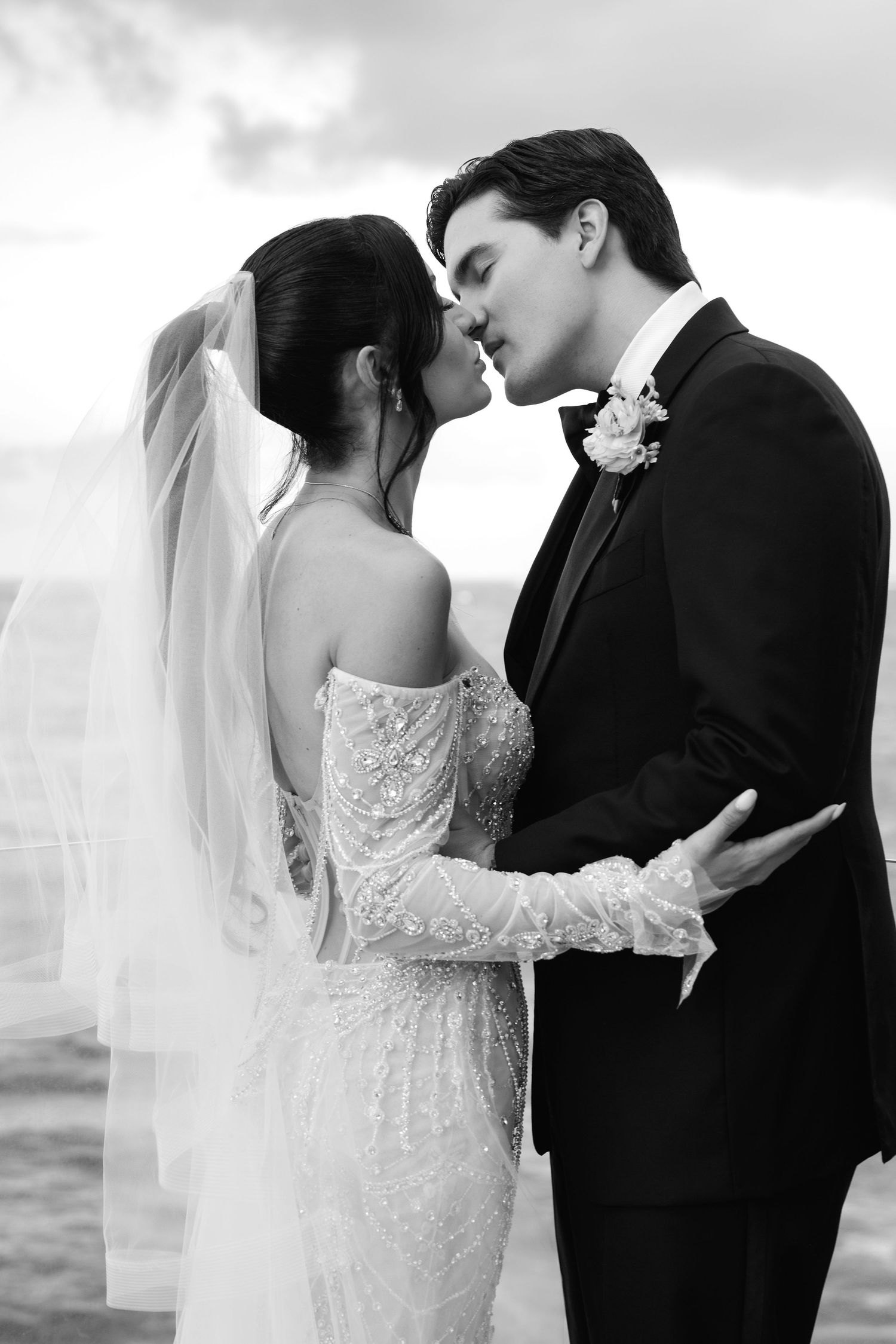 A romantic black and white wedding photo collage showing four intimate moments between a bride and groom by the ocean.