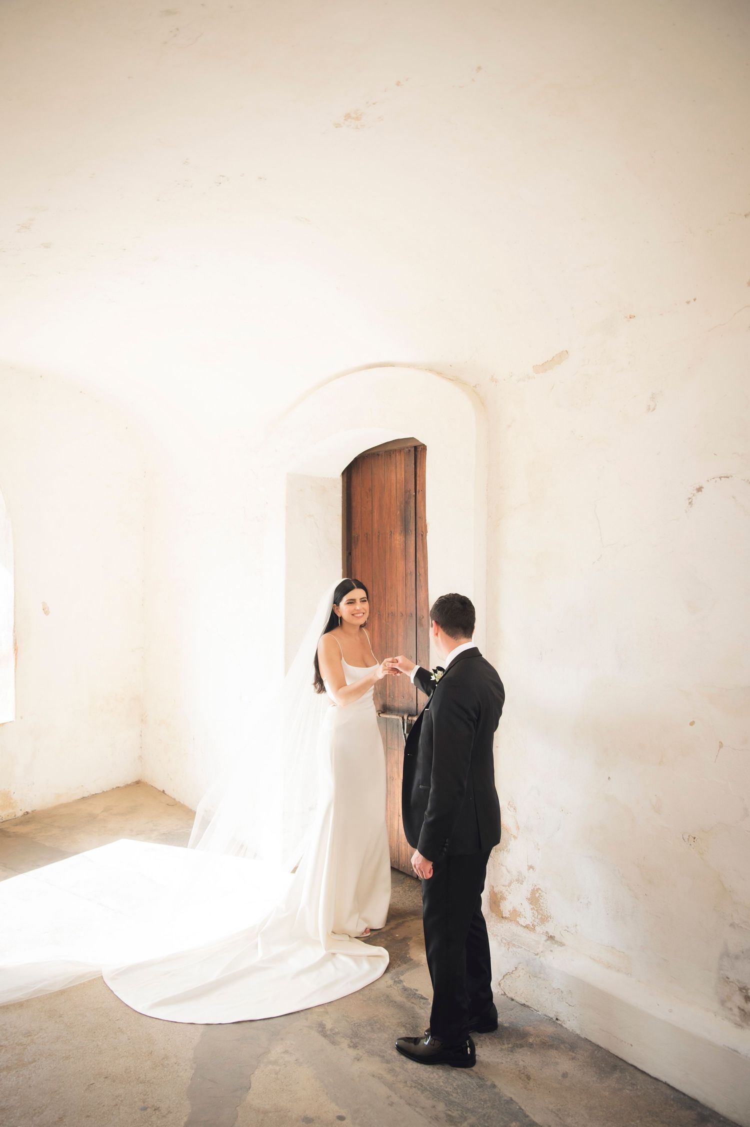 Wedding portraits captured in a minimalist white room with arched doorways and soft natural light.